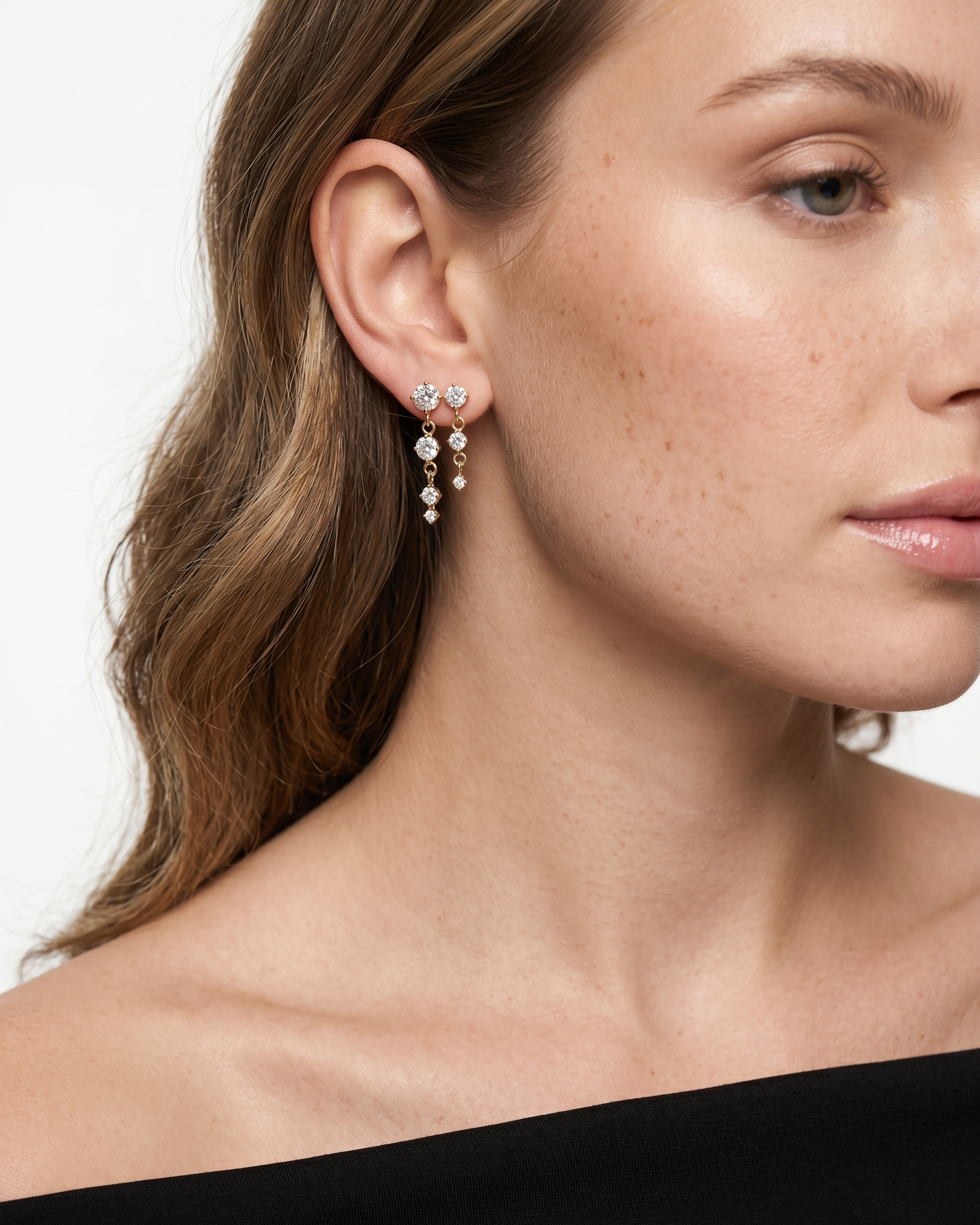 Close-up of a woman wearing a pair of earrings with a plain background