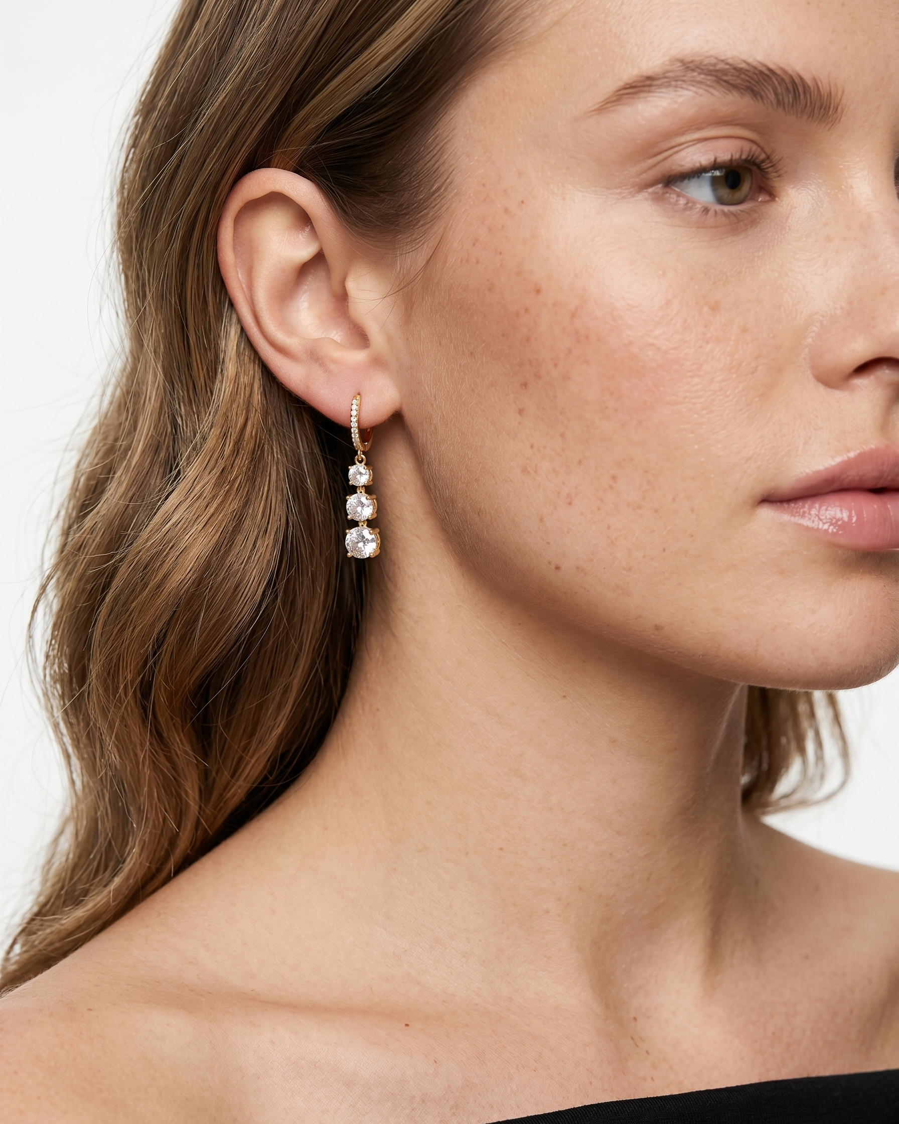 Close-up of a woman wearing a dangling earring with a white background