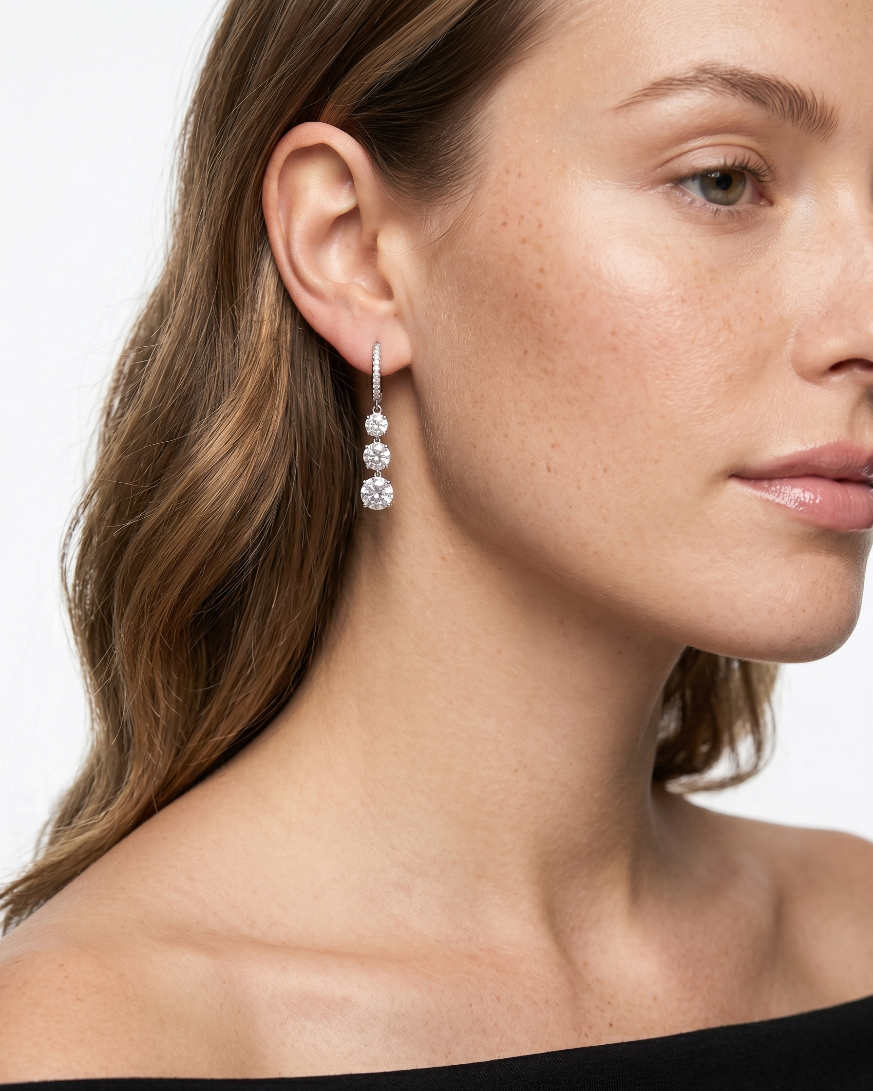 Close-up of a woman wearing a dangling earring with a white background