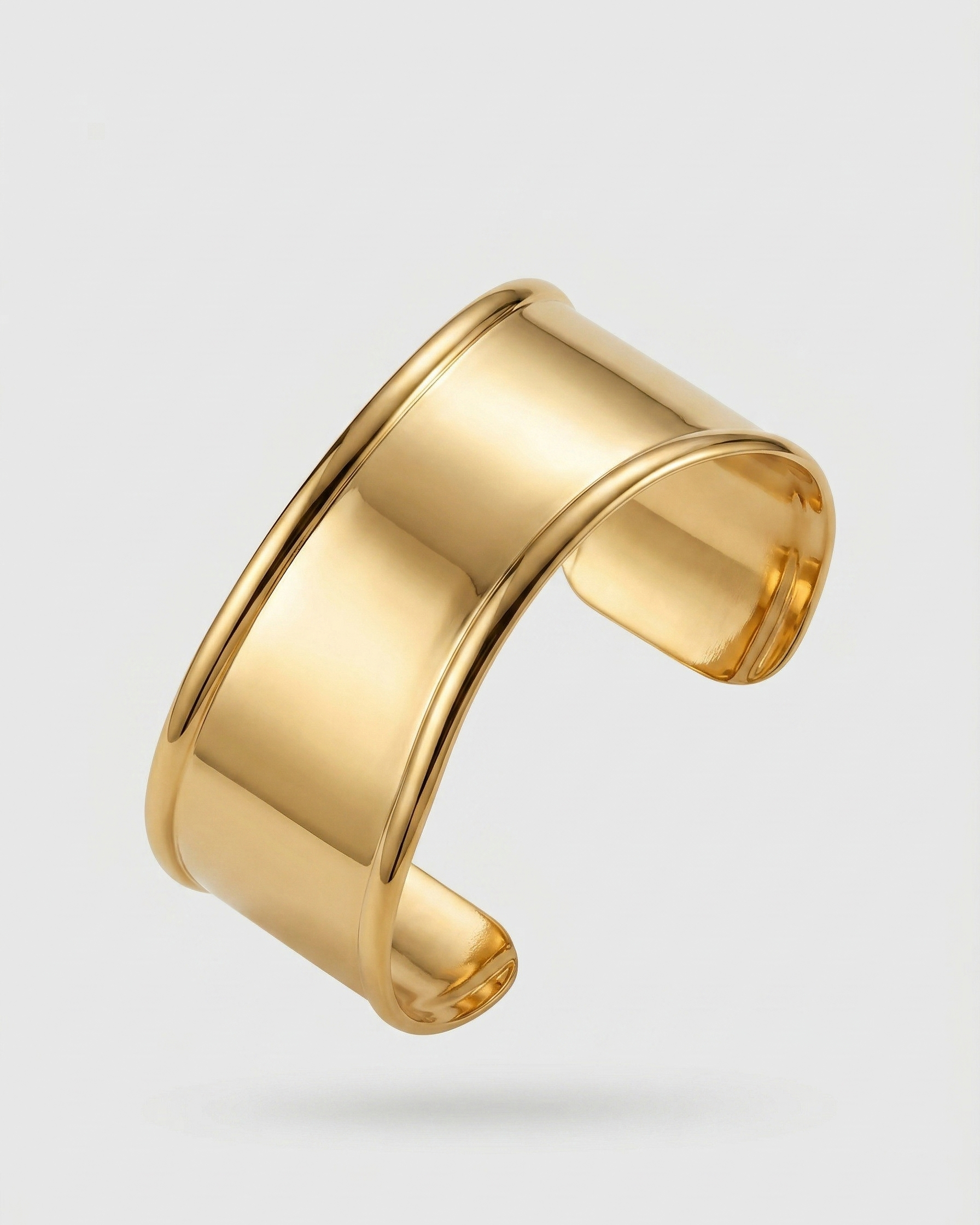 Gold cuff bracelet on a light gray background