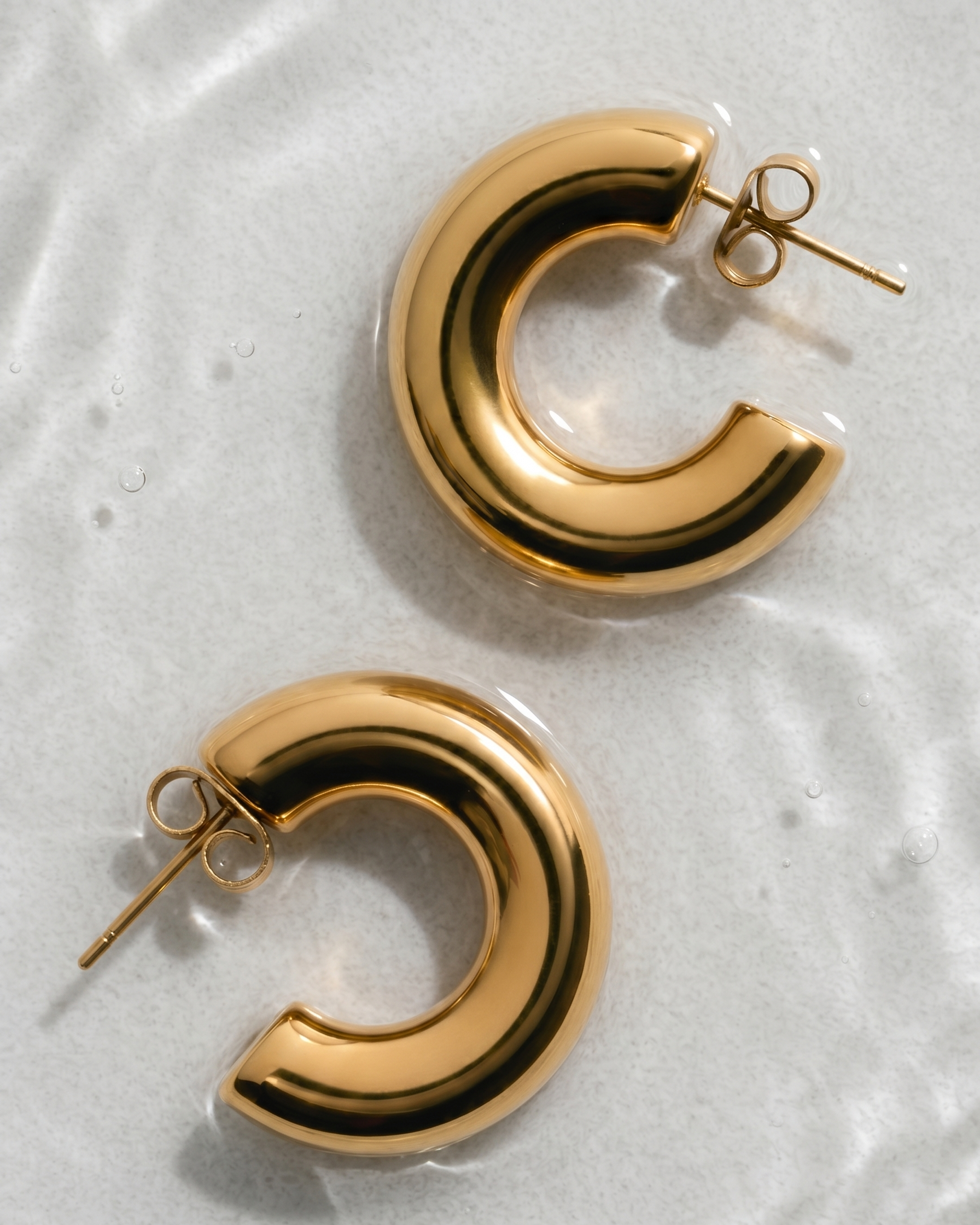 Gold hoop earrings on a textured white surface