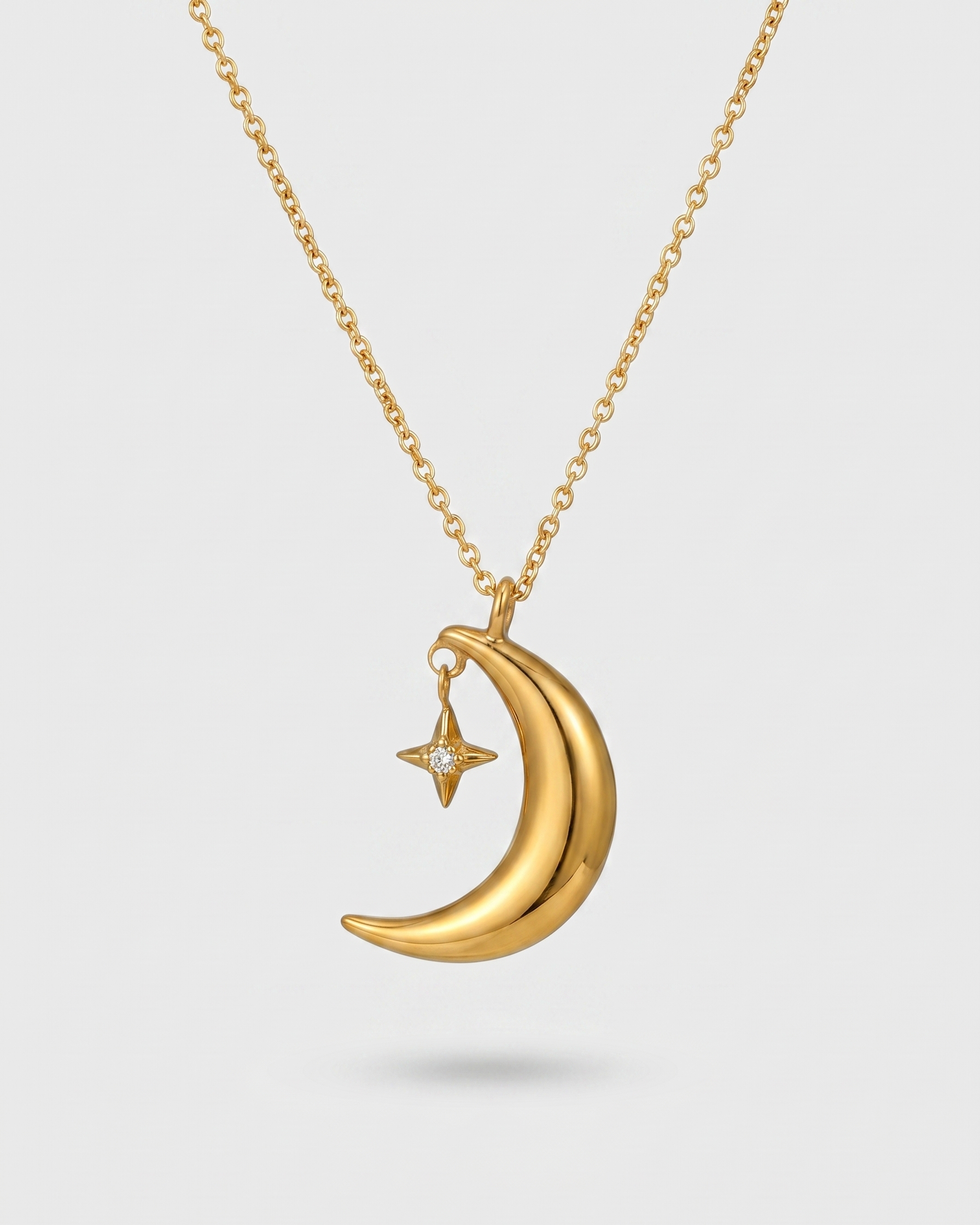 Gold necklace with a crescent moon and star pendant on a light gray background