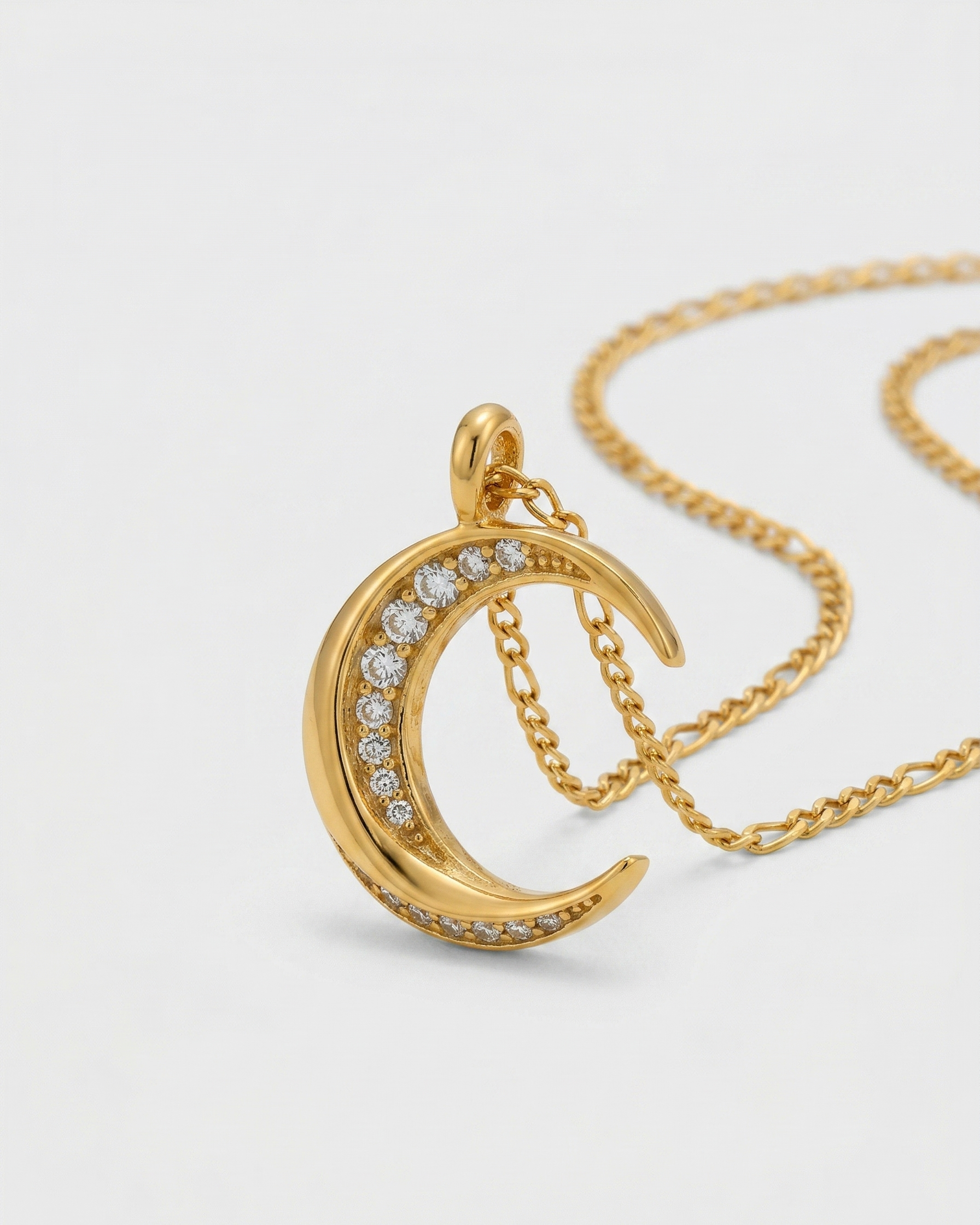 Gold necklace with a crescent moon pendant on a light gray background