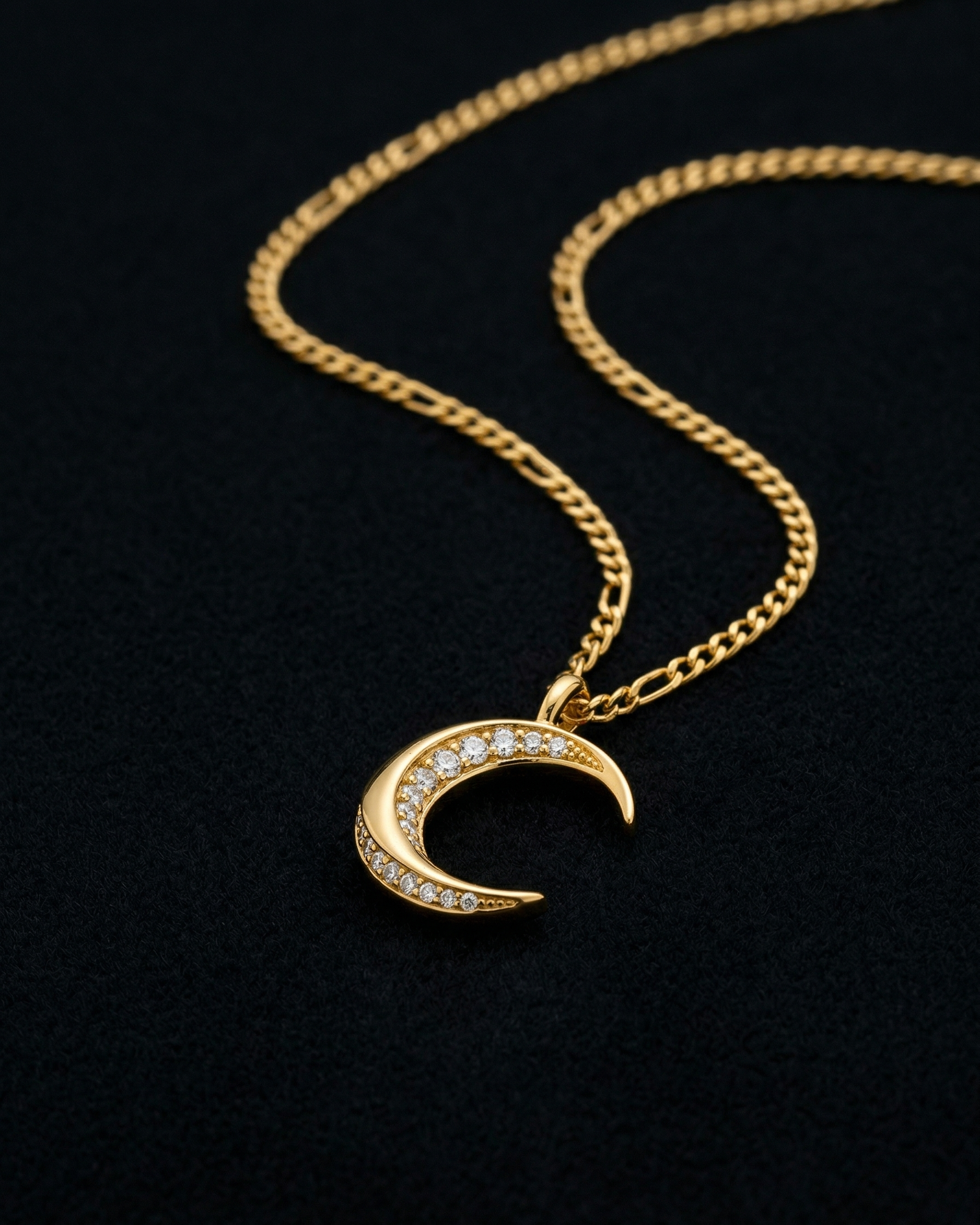 Gold necklace with a crescent moon pendant on a black background