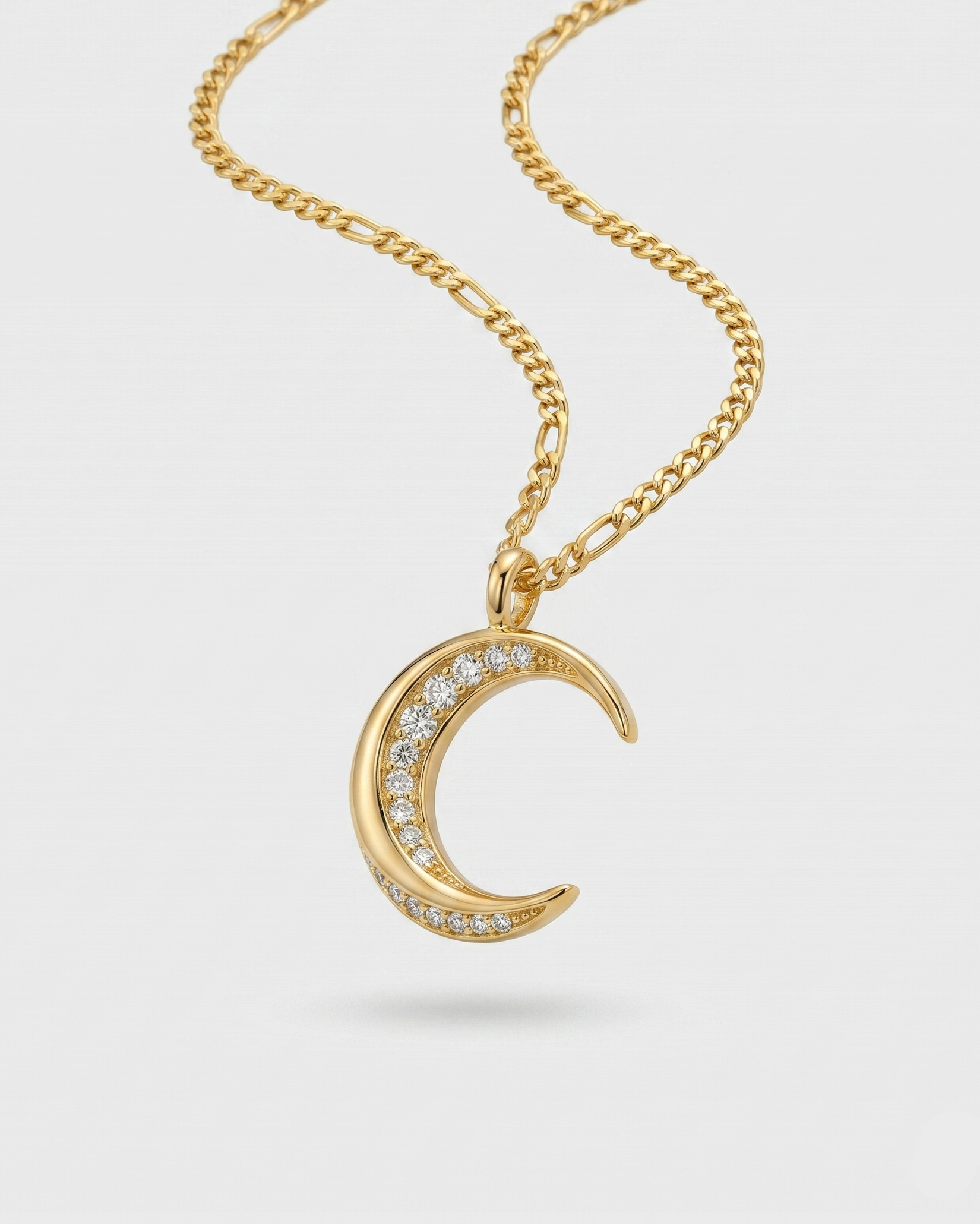 Gold necklace with a crescent moon pendant on a light gray background