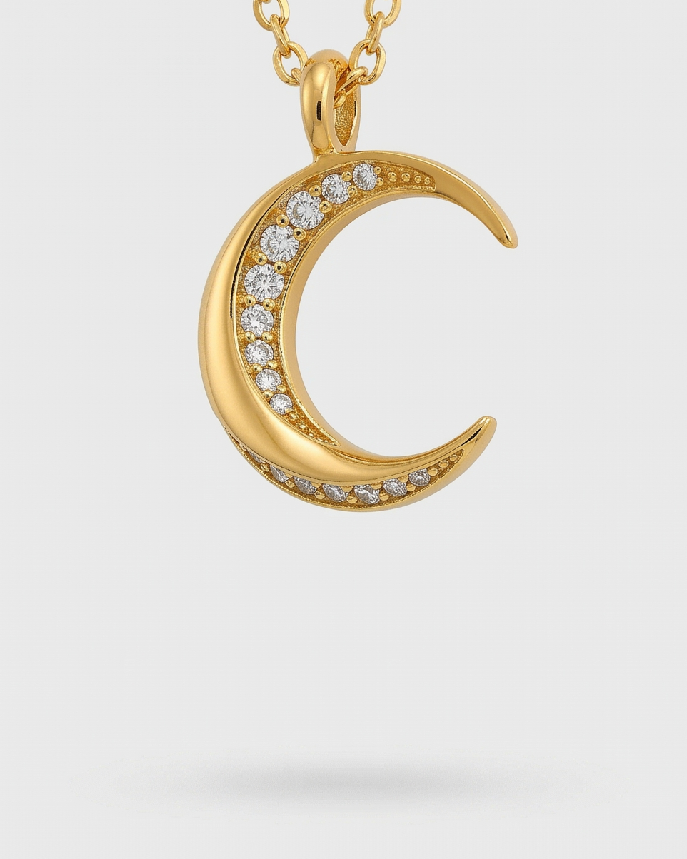 Gold necklace with a crescent moon pendant on a light gray background
