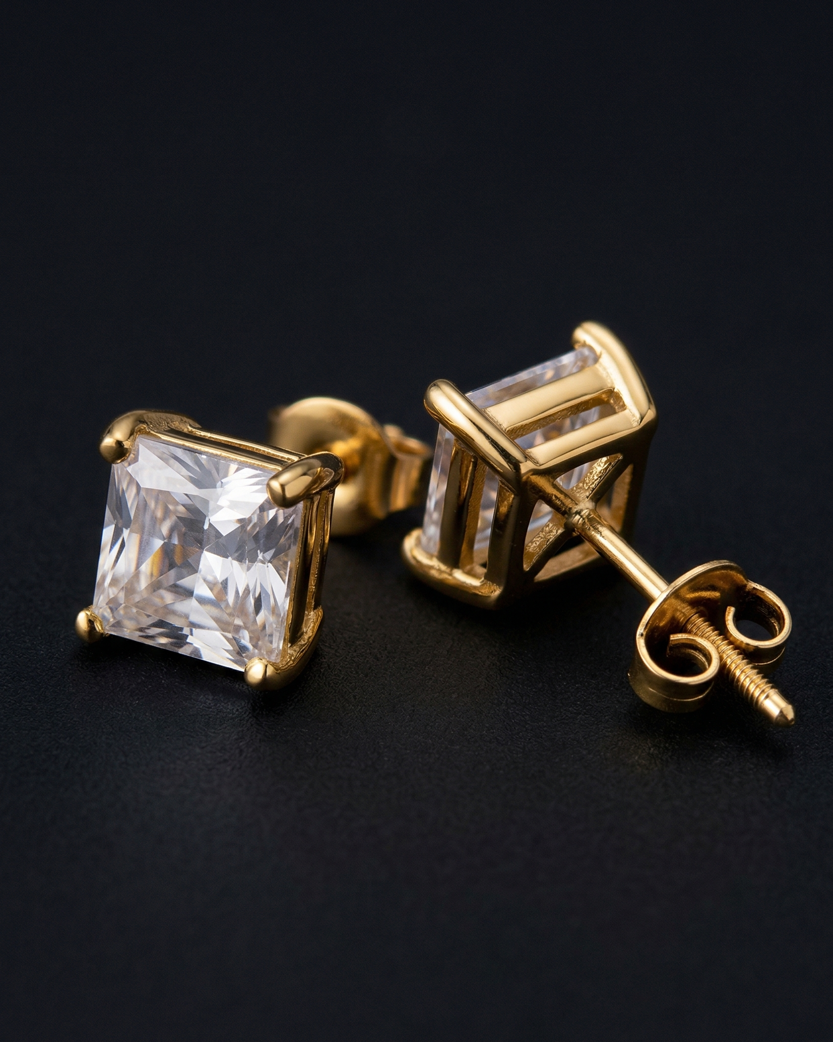 Gold earrings with clear gemstones on a black background