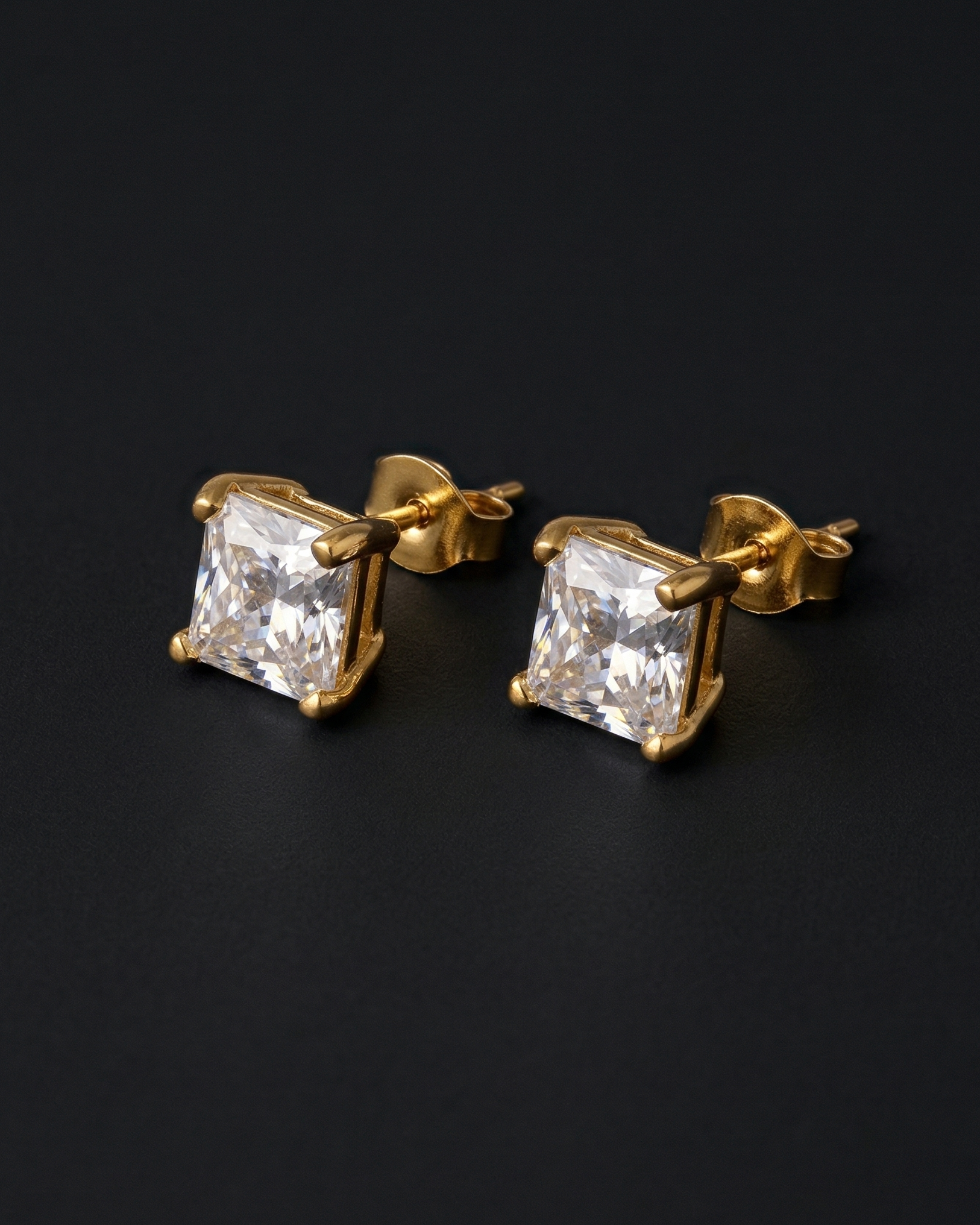 Gold square-cut gemstone earrings on a black background
