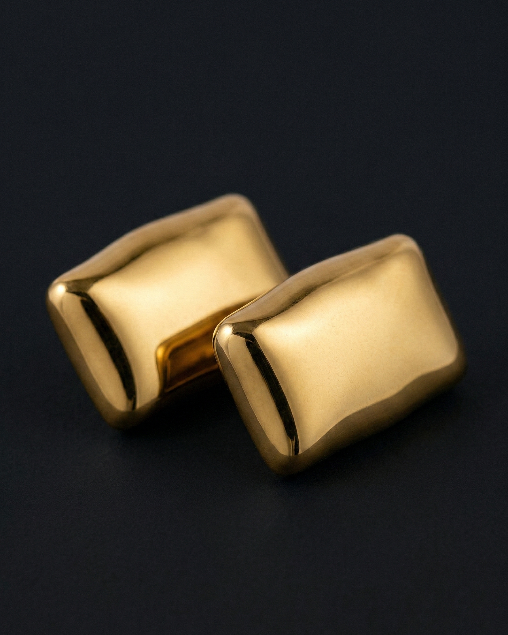 Pair of gold rectangular cufflinks on a black background