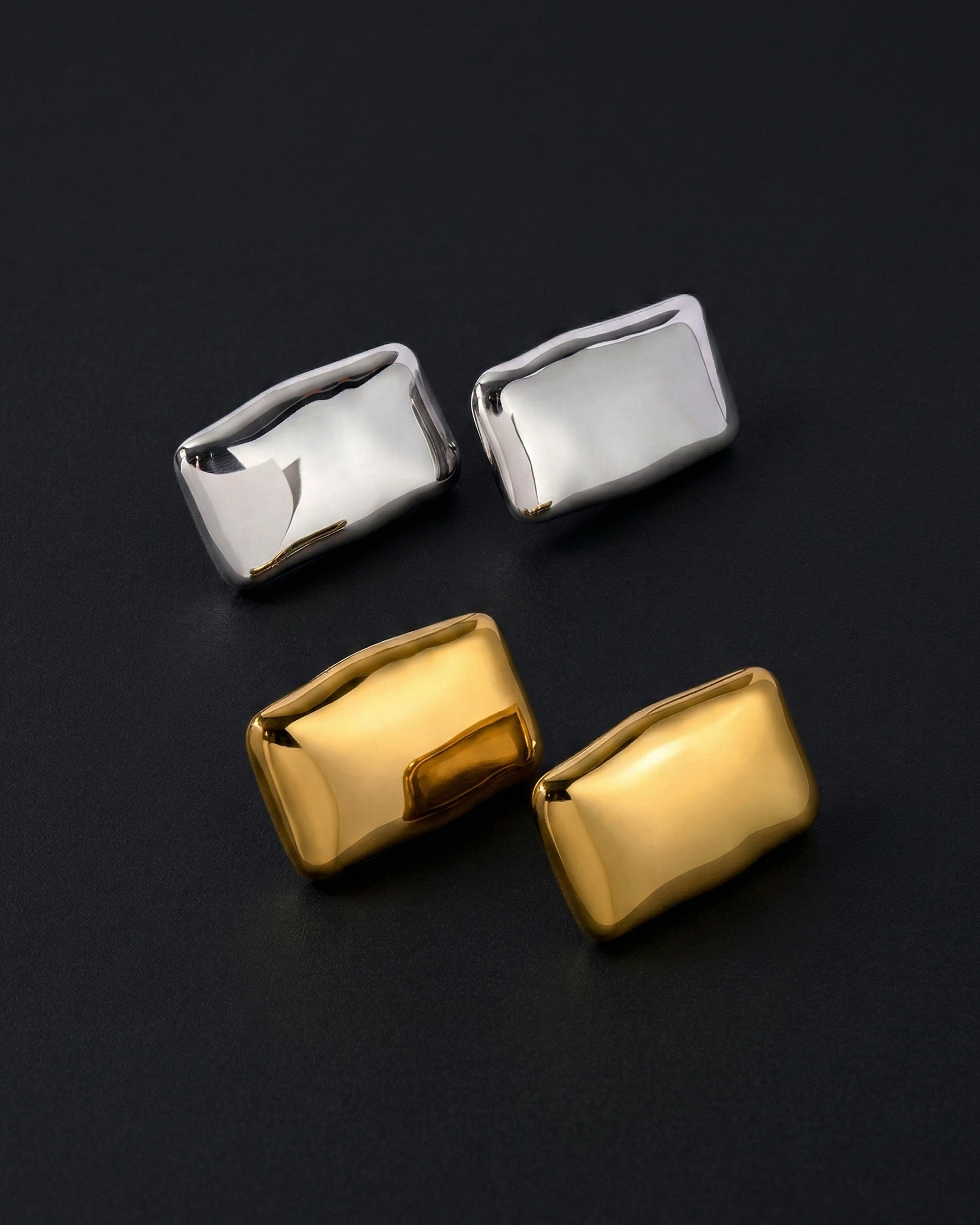 Two pairs of silver and gold rectangular cufflinks on a black background