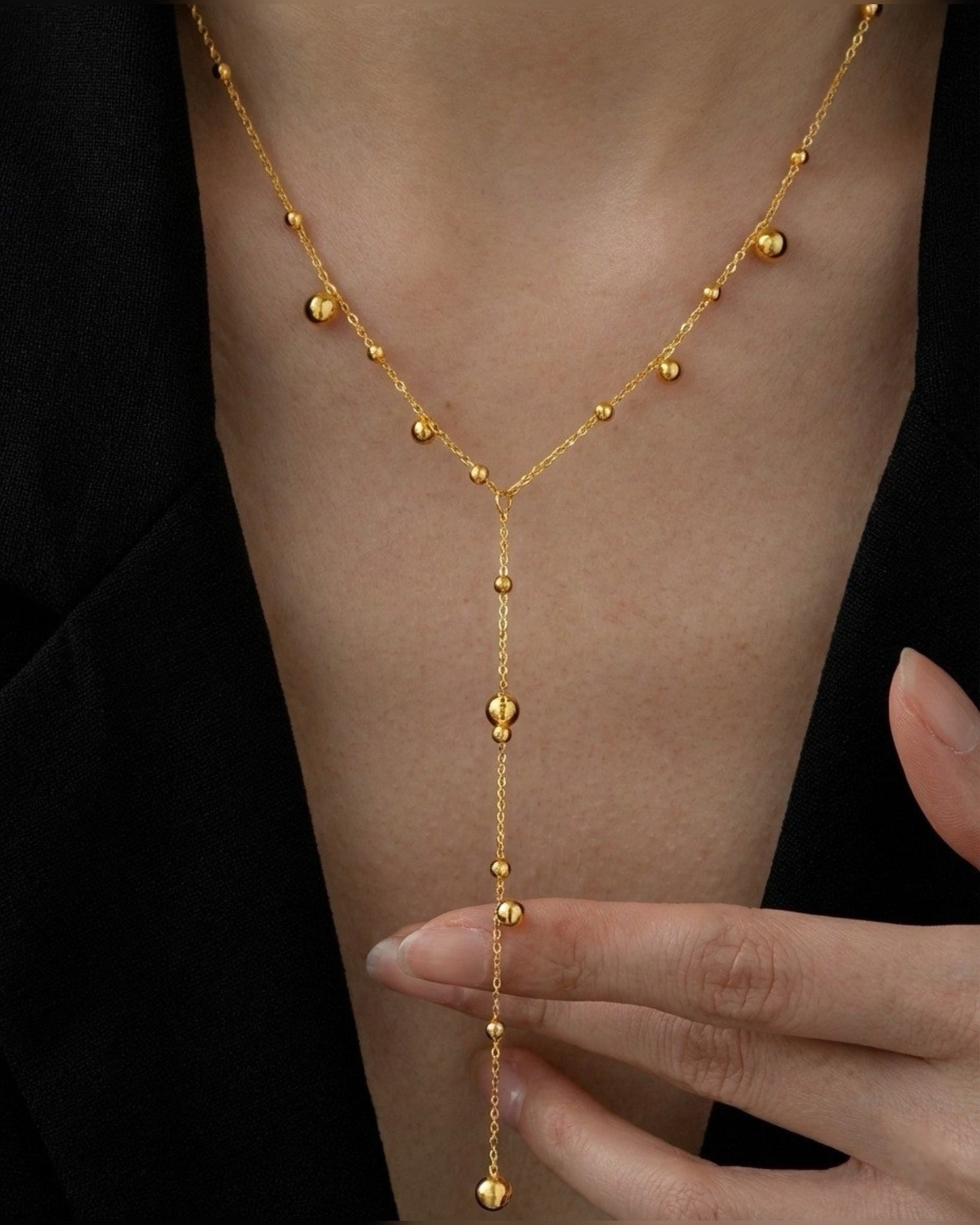 Gold body chain worn by a person against a black background