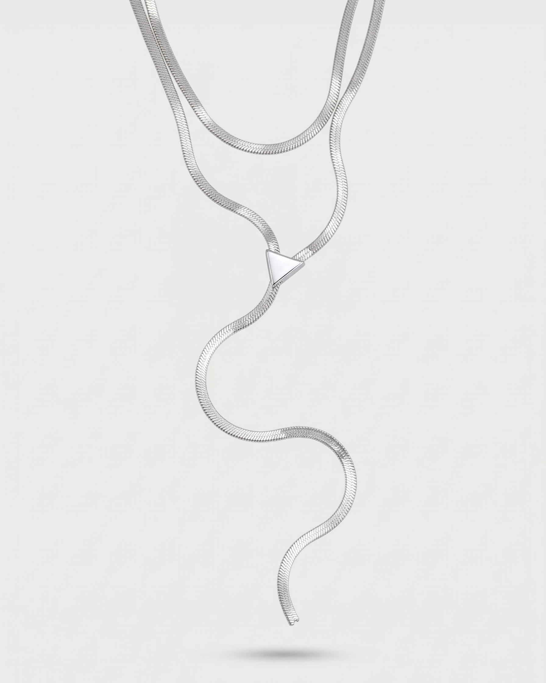Silver snake-shaped necklace on a light gray background