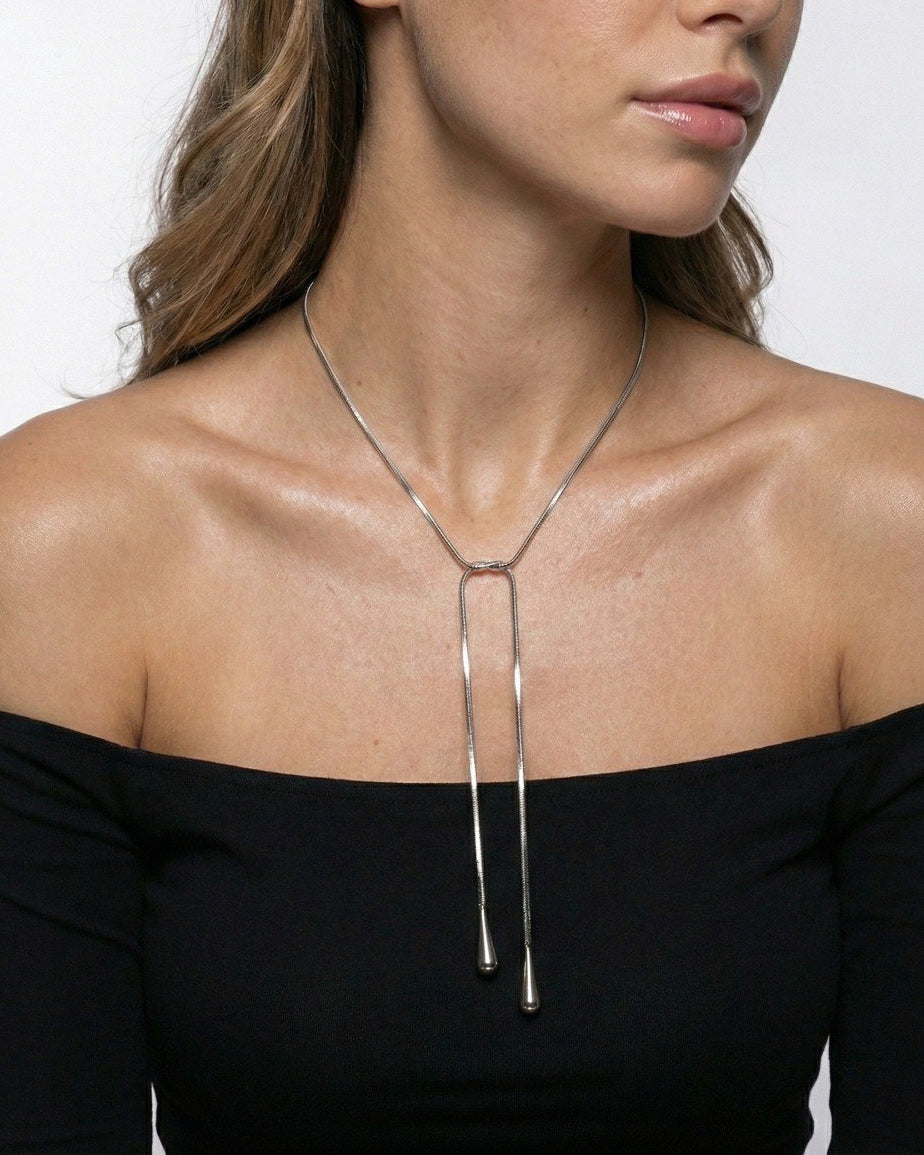 Silver lariat necklace worn by a model against a neutral background
