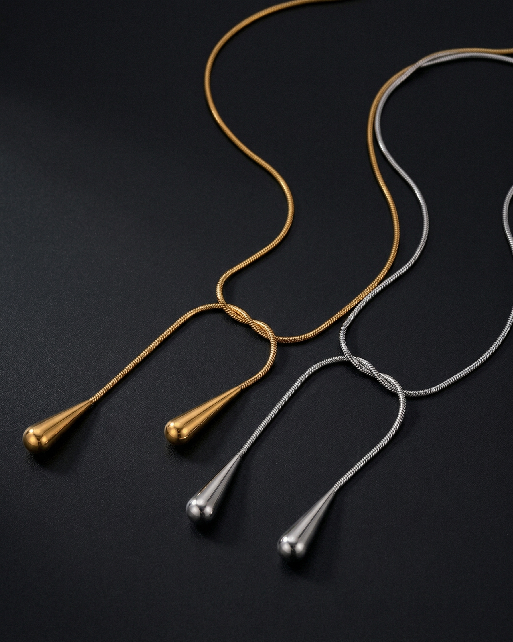 Two necklaces, one gold and one silver, on a dark background