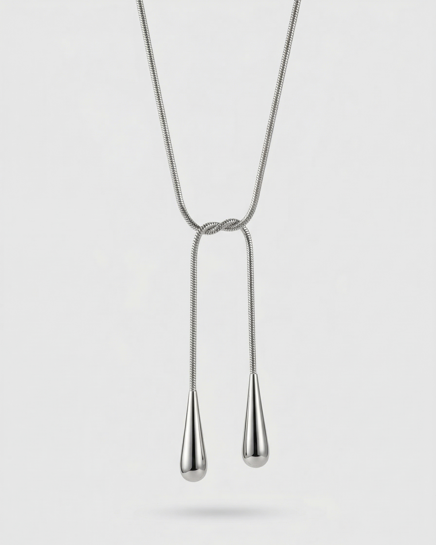 Silver necklace with two teardrop pendants on a white background