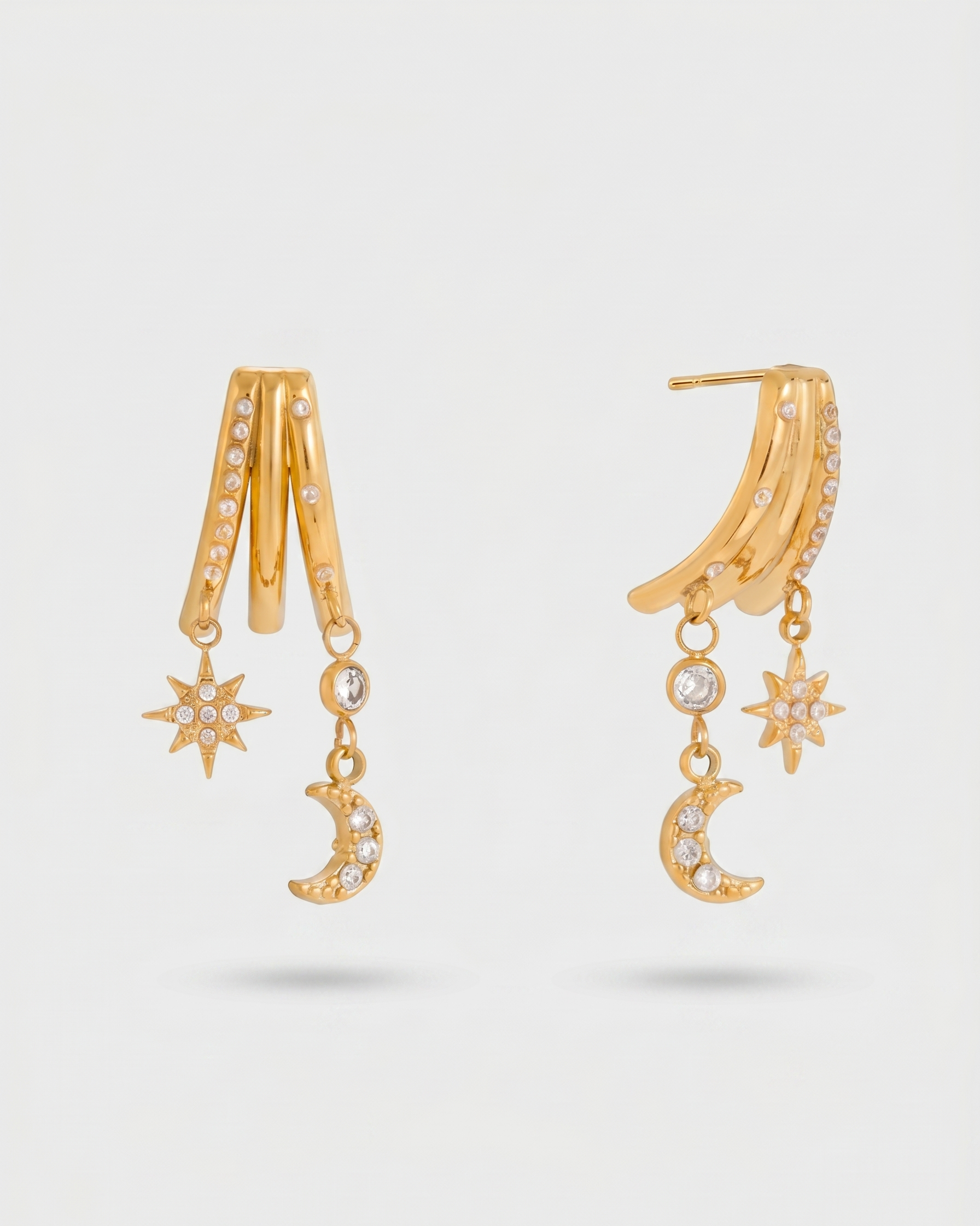 Gold earrings with star and moon designs on a light gray background
