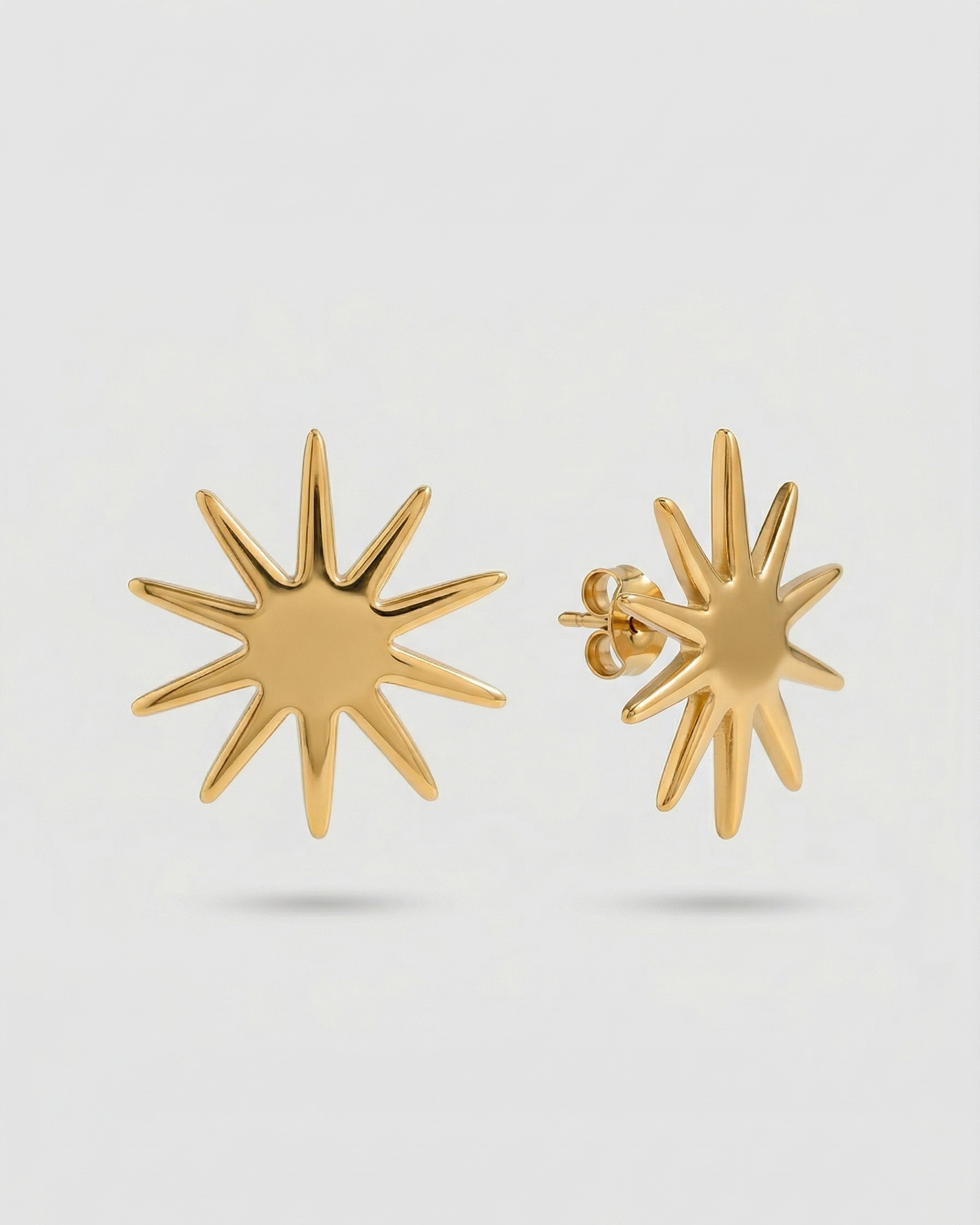 Gold star-shaped earrings on a light gray background