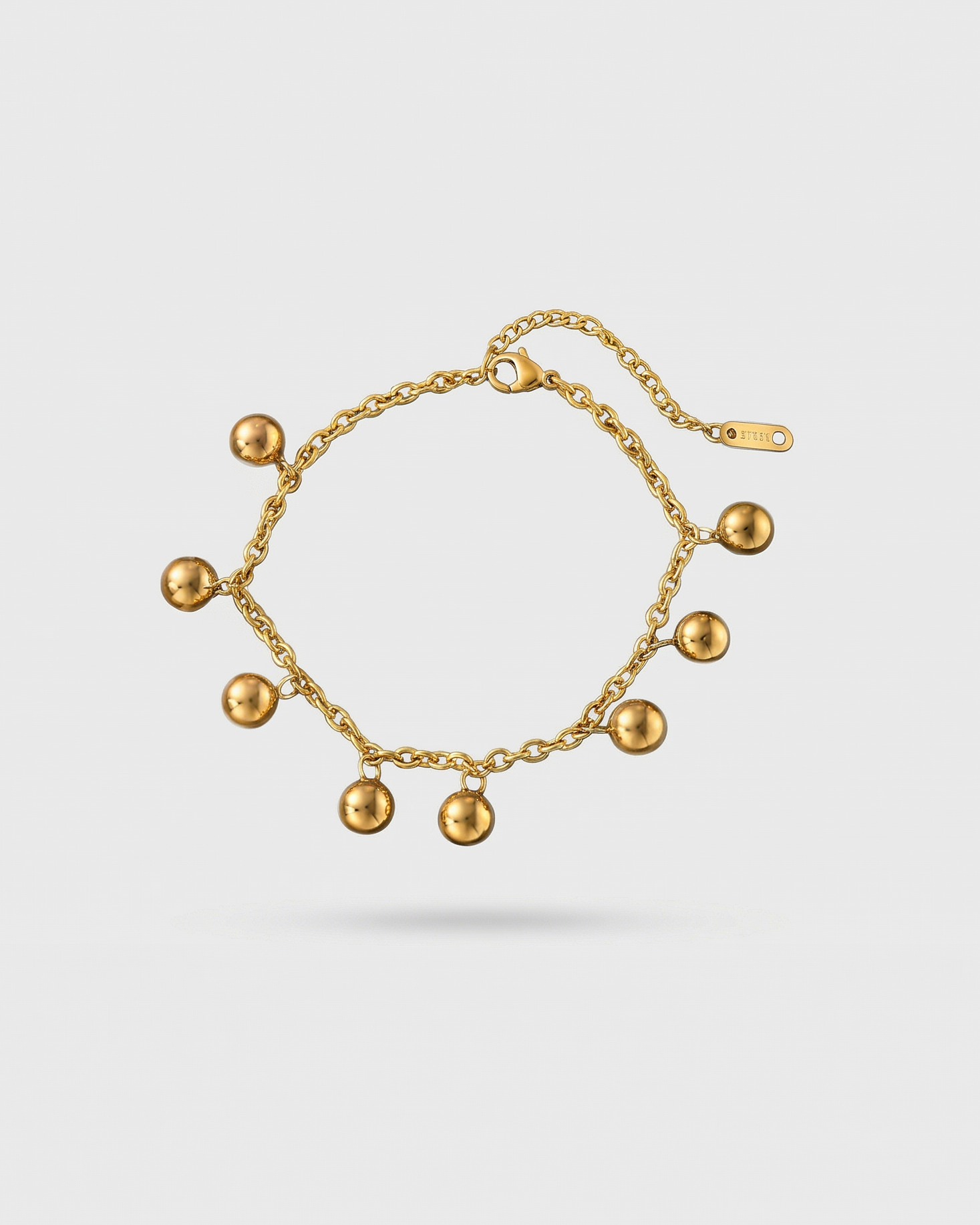 Gold bracelet with spherical charms on a white background