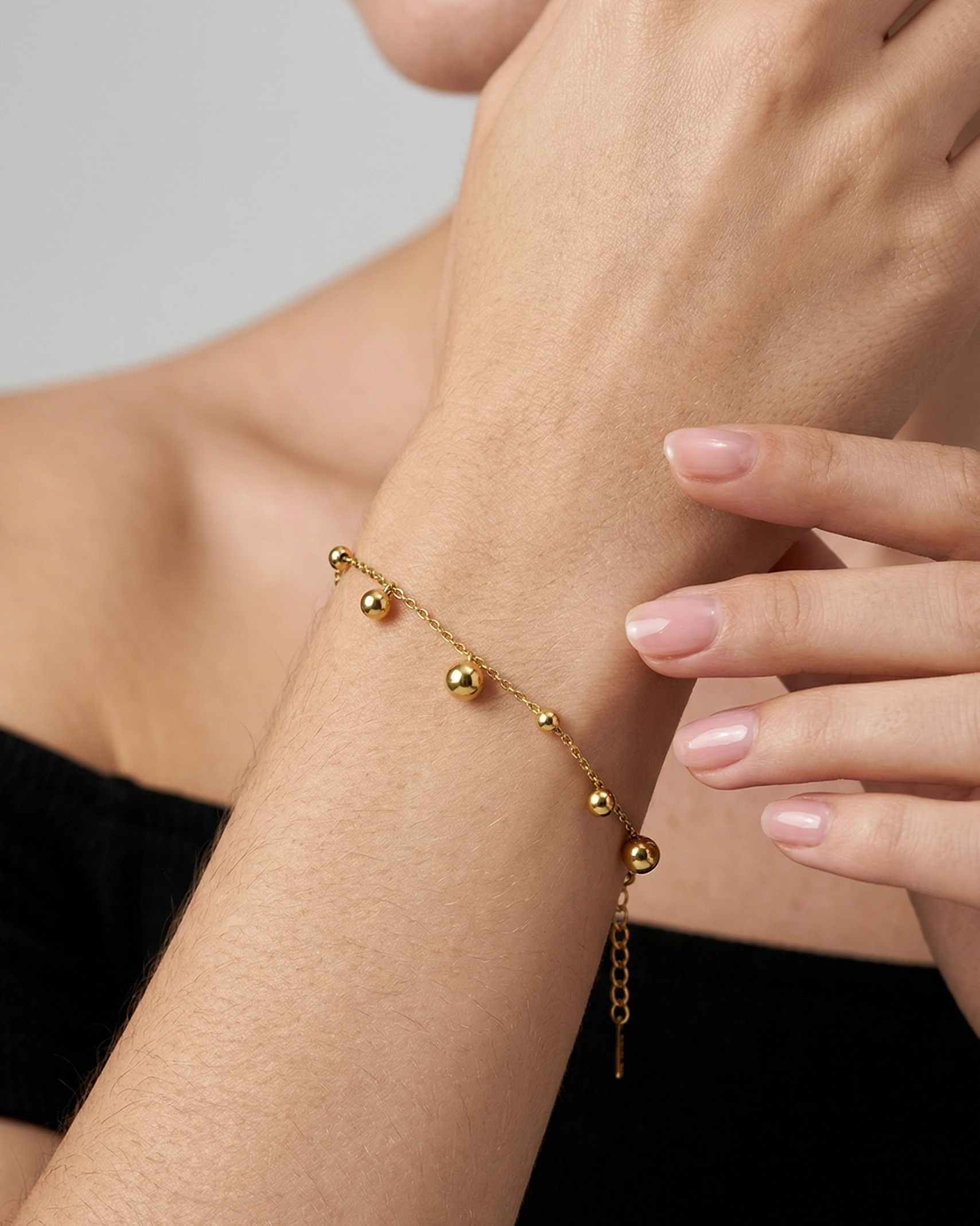 Gold bracelet on a wrist with a neutral background