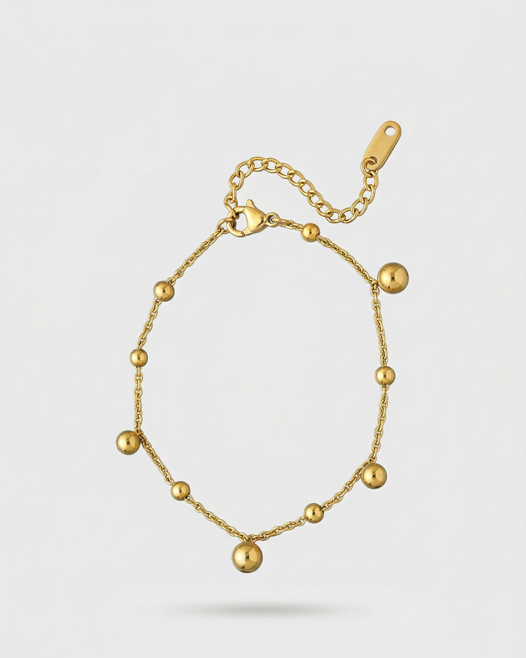 Gold bracelet with spherical beads on a light gray background