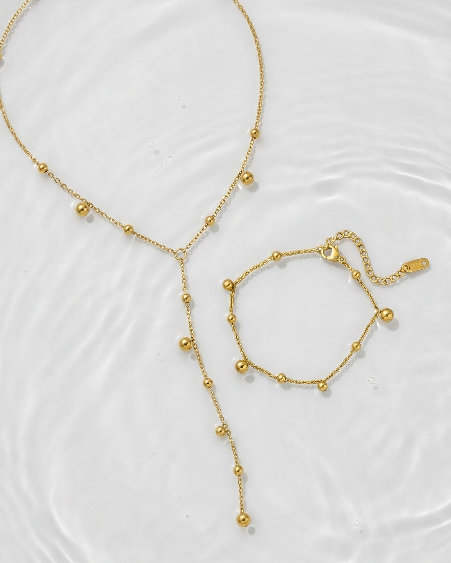 Gold necklace and bracelet set on a white background