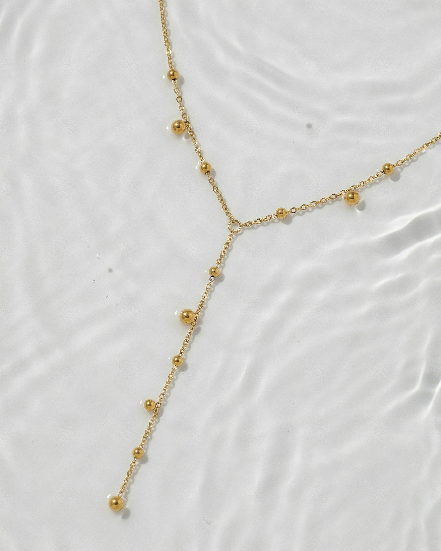 Gold necklace on a white textured surface