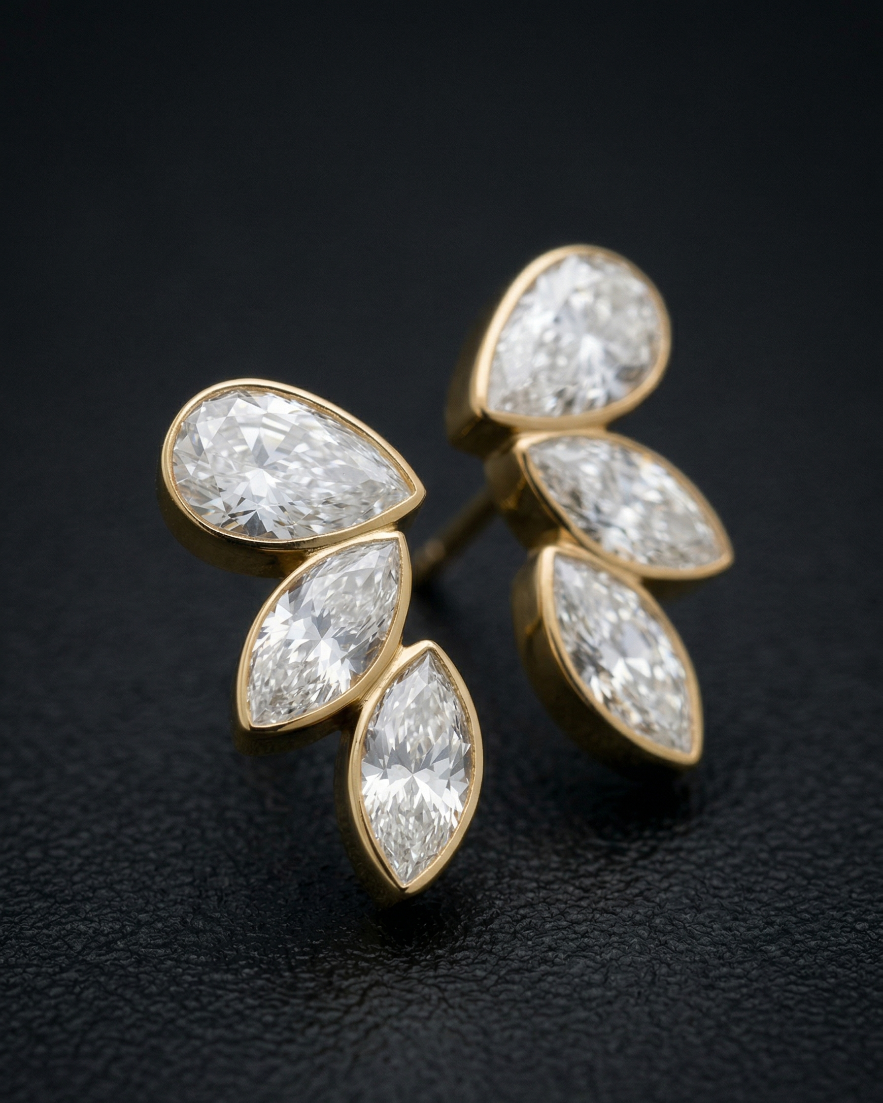 Pair of diamond earrings with gold setting on a dark background