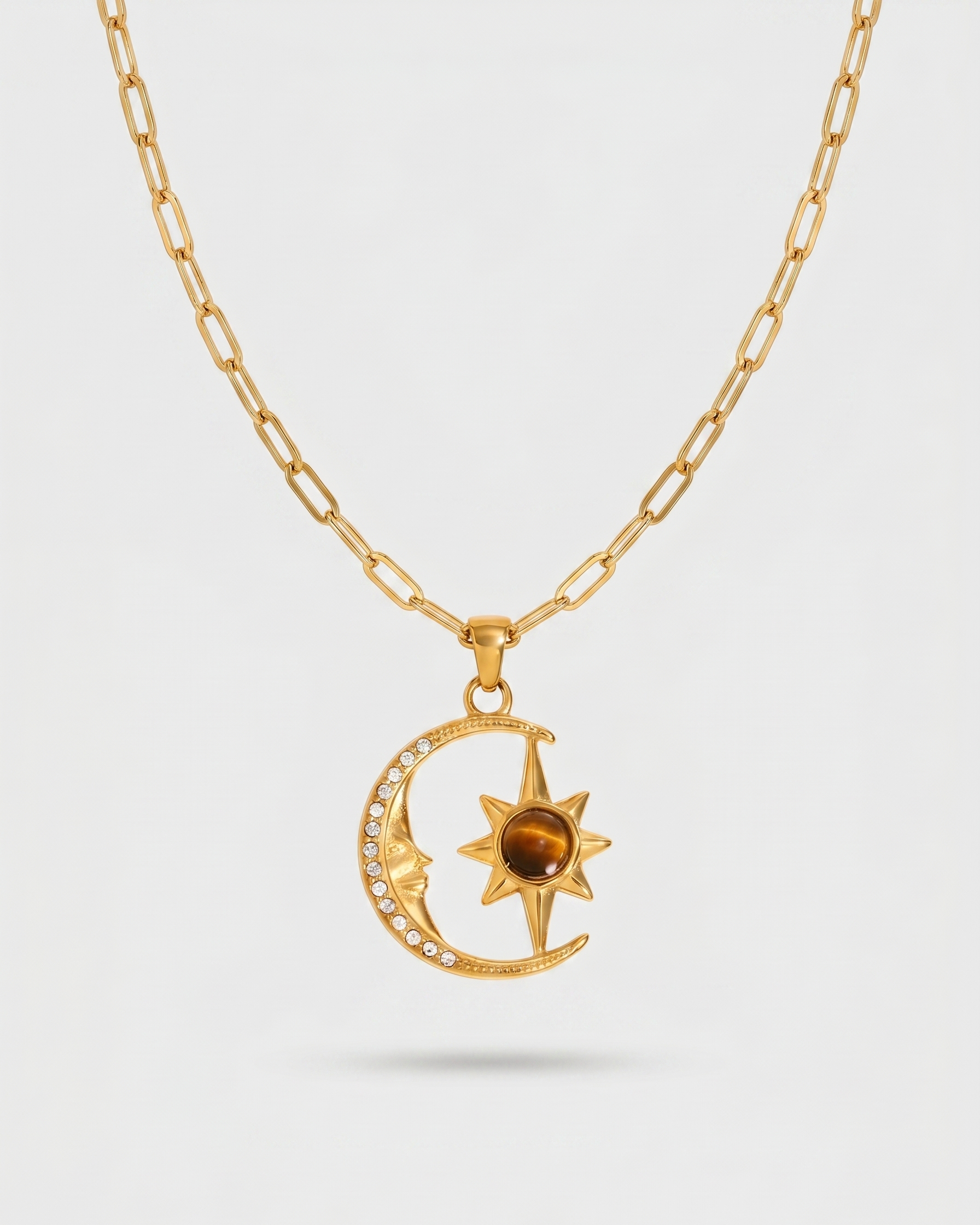 Gold necklace with a moon and star pendant on a light gray background