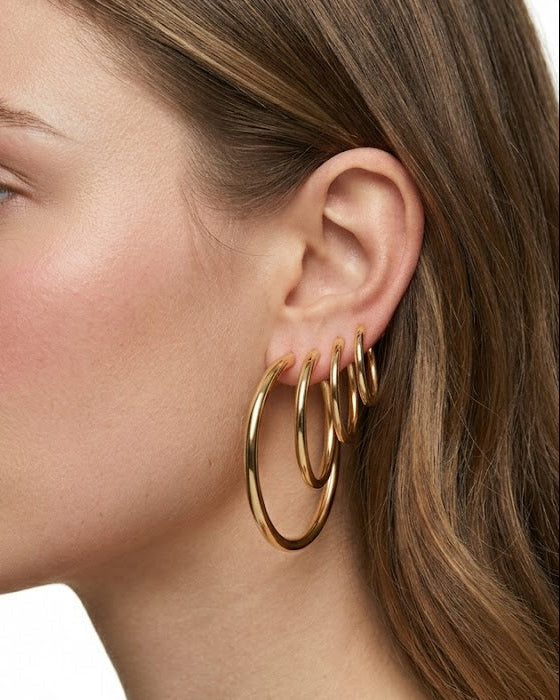 Woman wearing gold hoop earrings on a white background