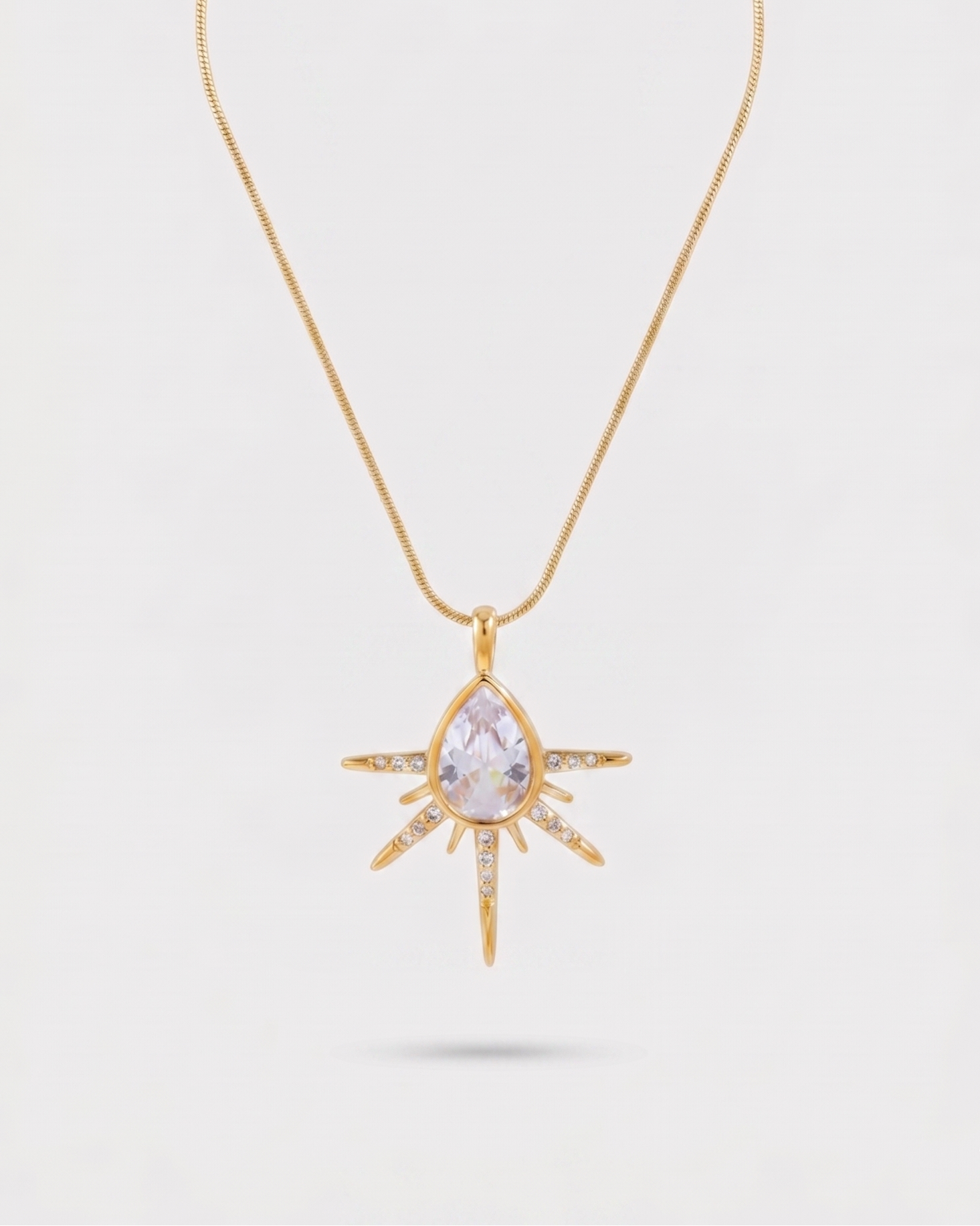Gold necklace with a star-shaped pendant on a light gray background