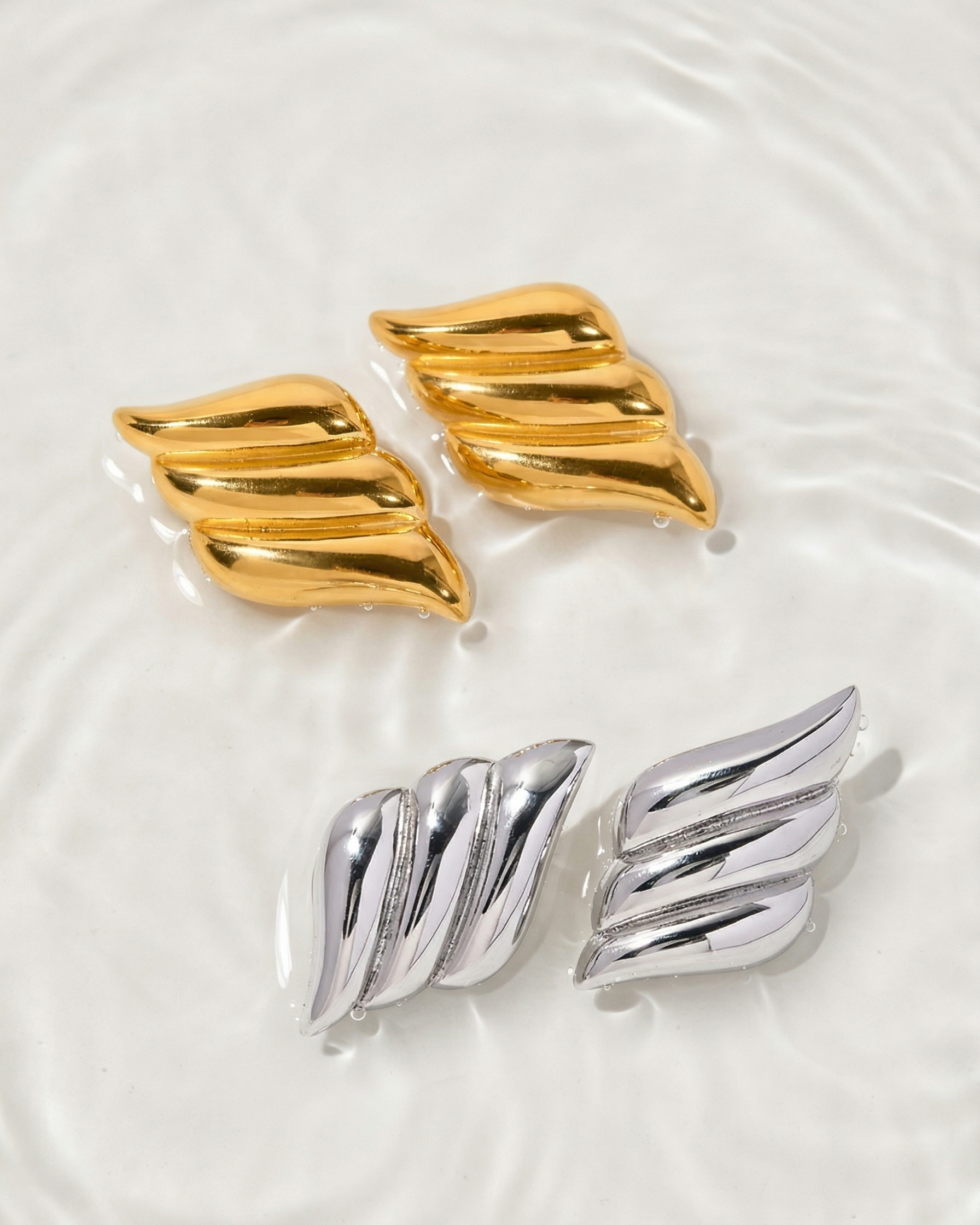 Pair of gold and silver wing-shaped earrings on a white background