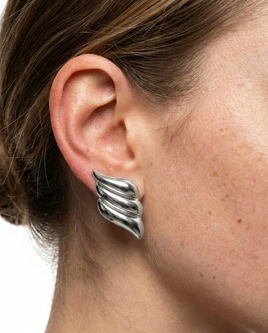 Close-up of a person wearing silver wing-shaped earrings.
