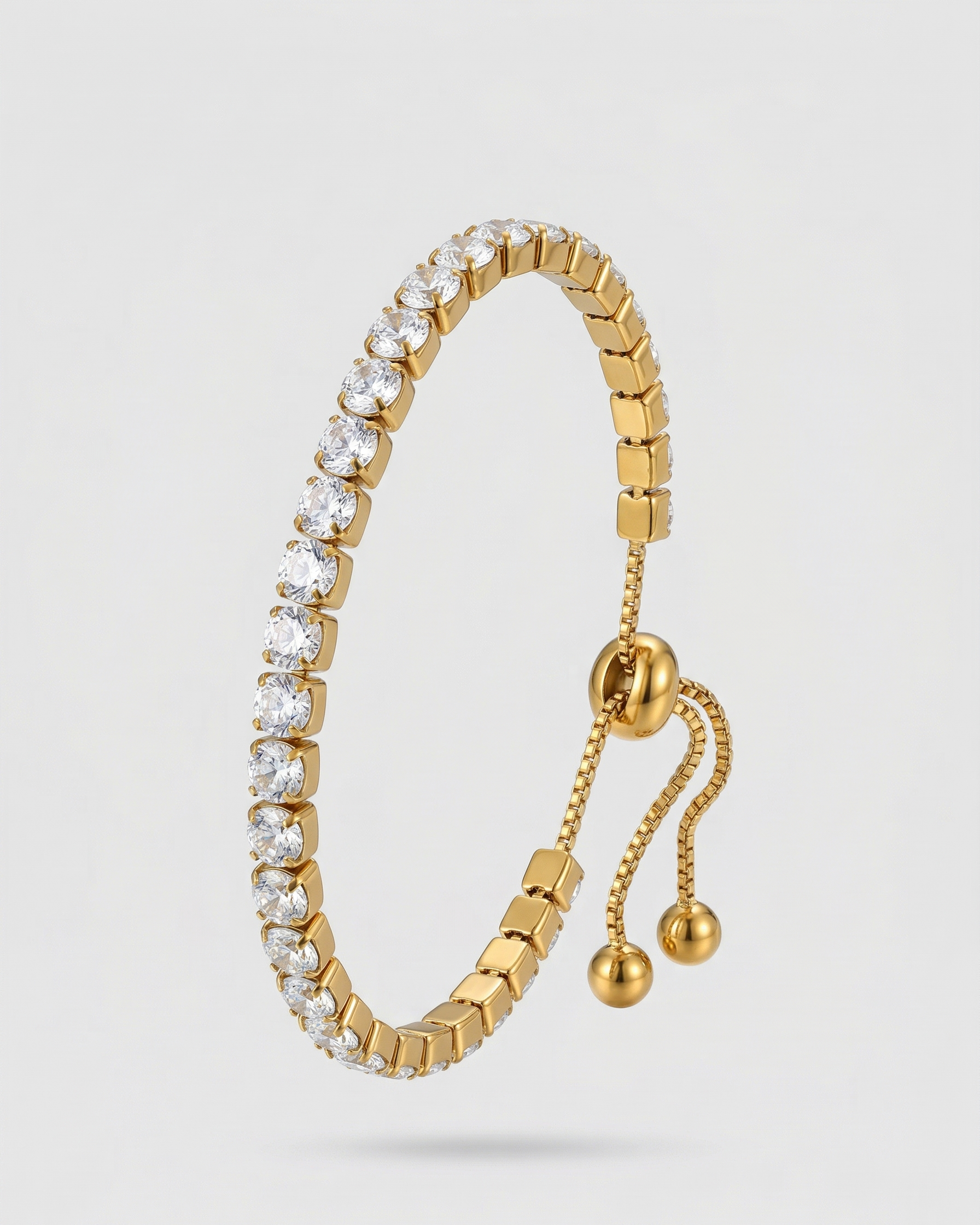 Gold bracelet with clear stones on a light gray background