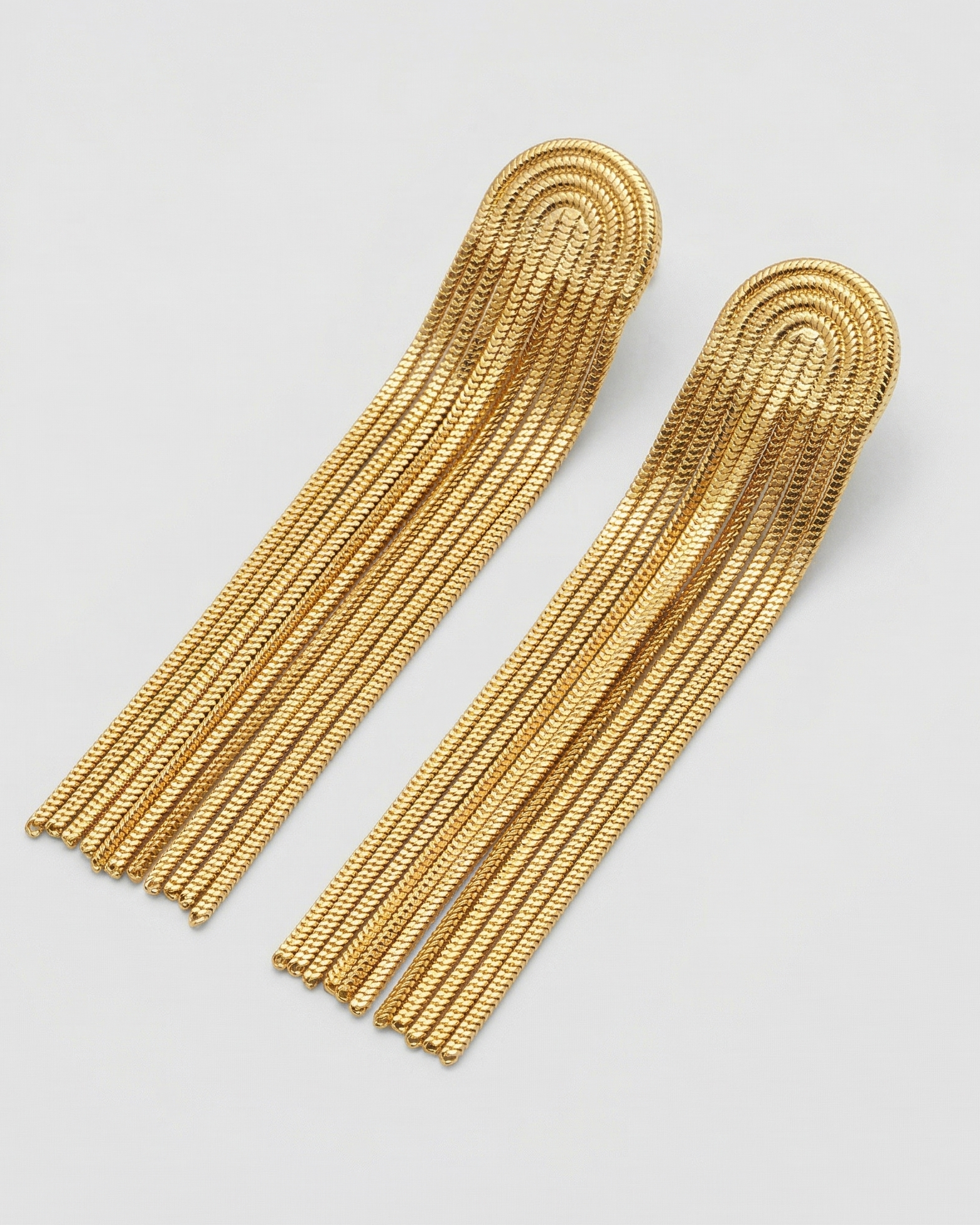 Pair of gold fringe earrings on a light gray background