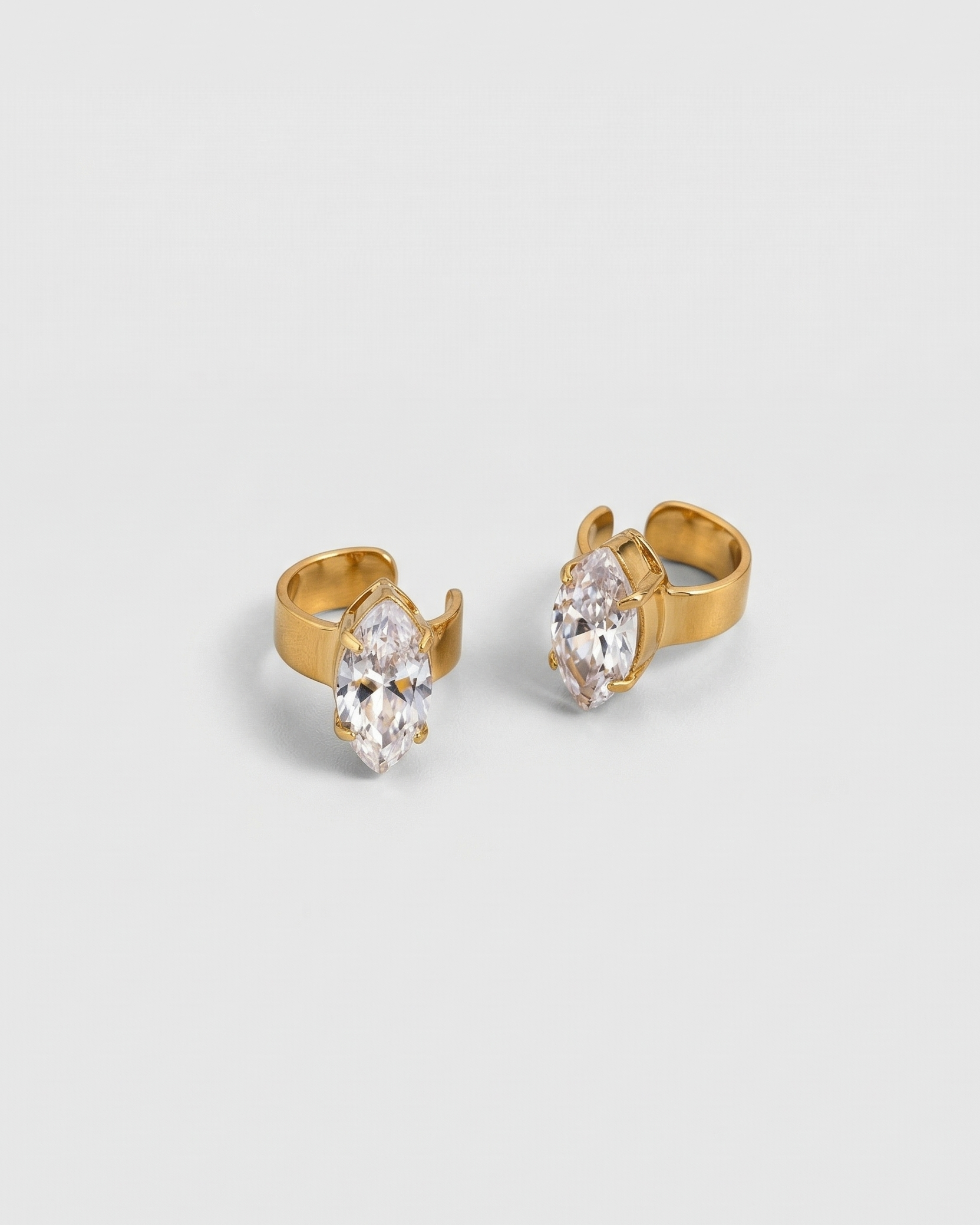Gold earrings with clear gemstones on a light gray background