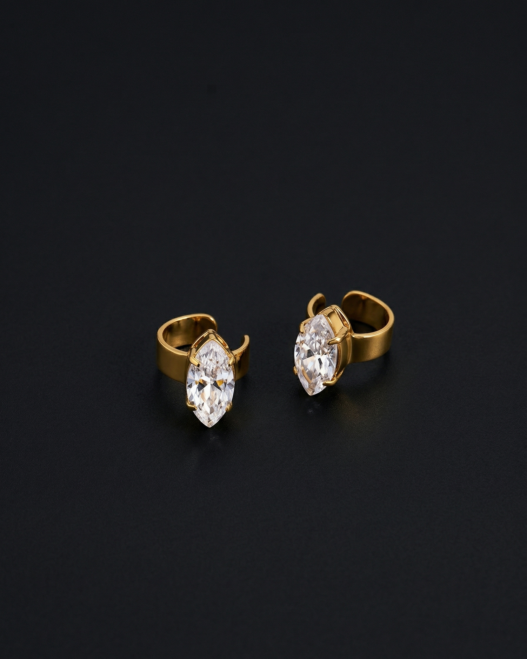 Gold earrings with clear gemstones on a black background