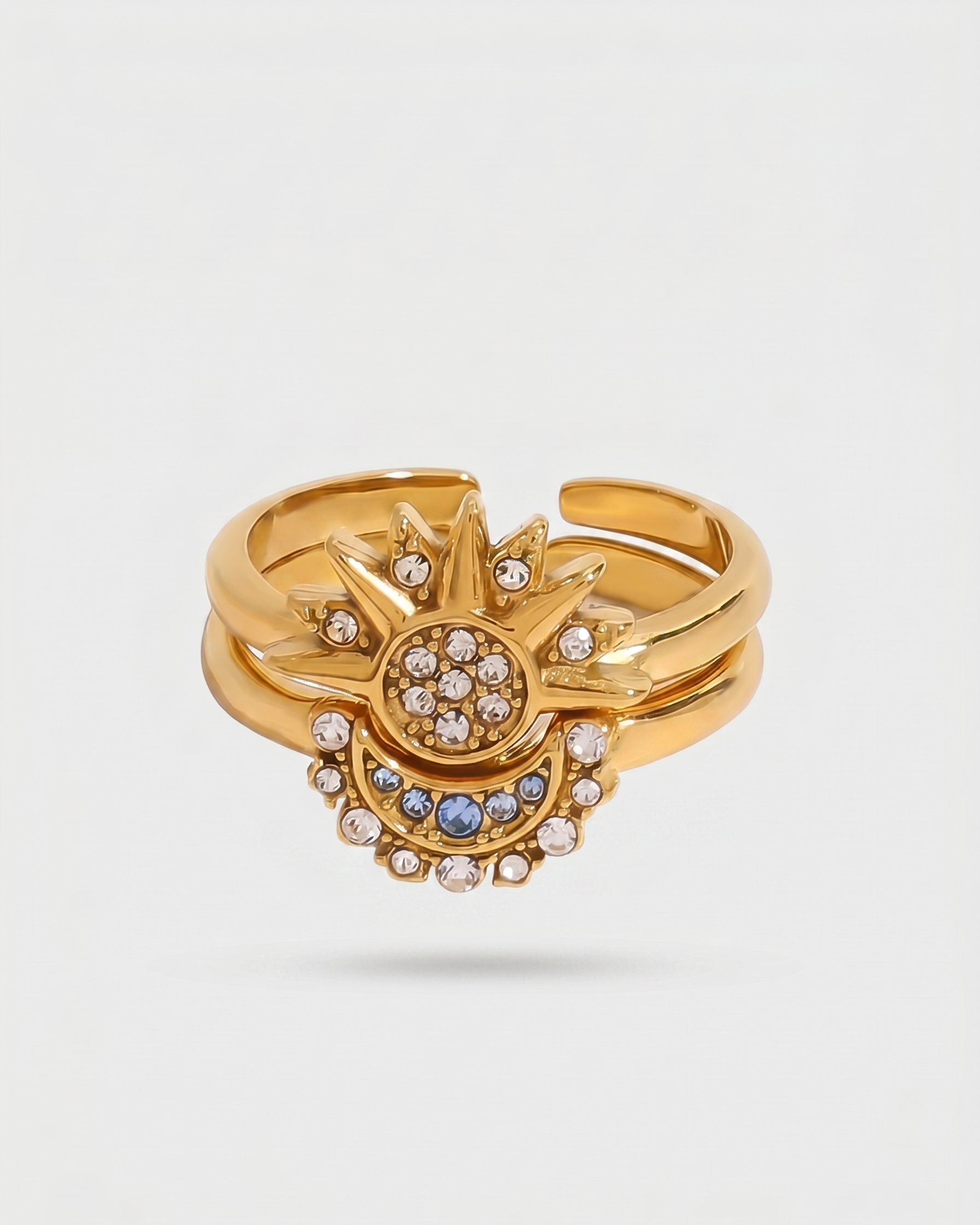 Gold ring with intricate design and gemstones on a light gray background