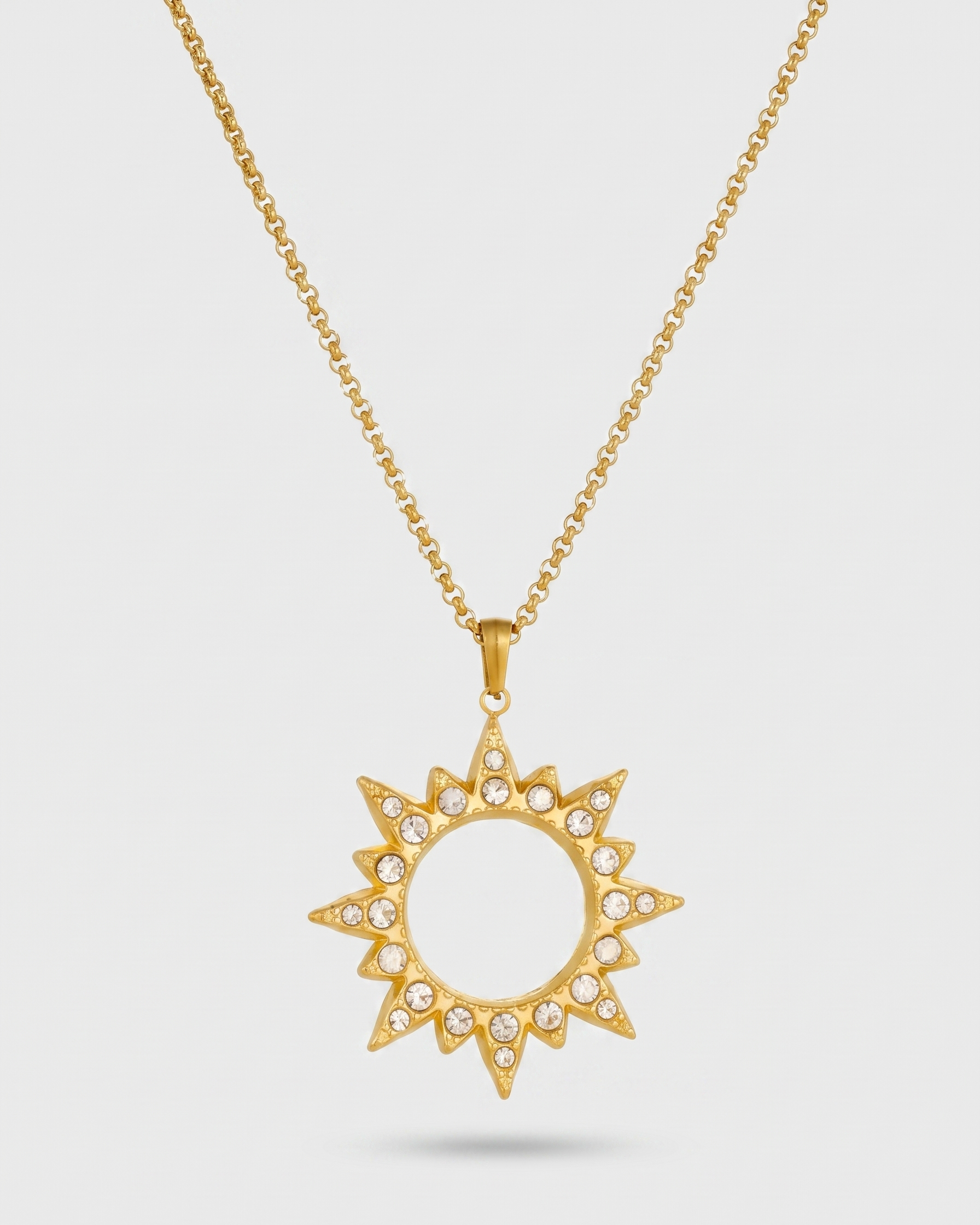 Gold sun-shaped pendant necklace on a light gray background