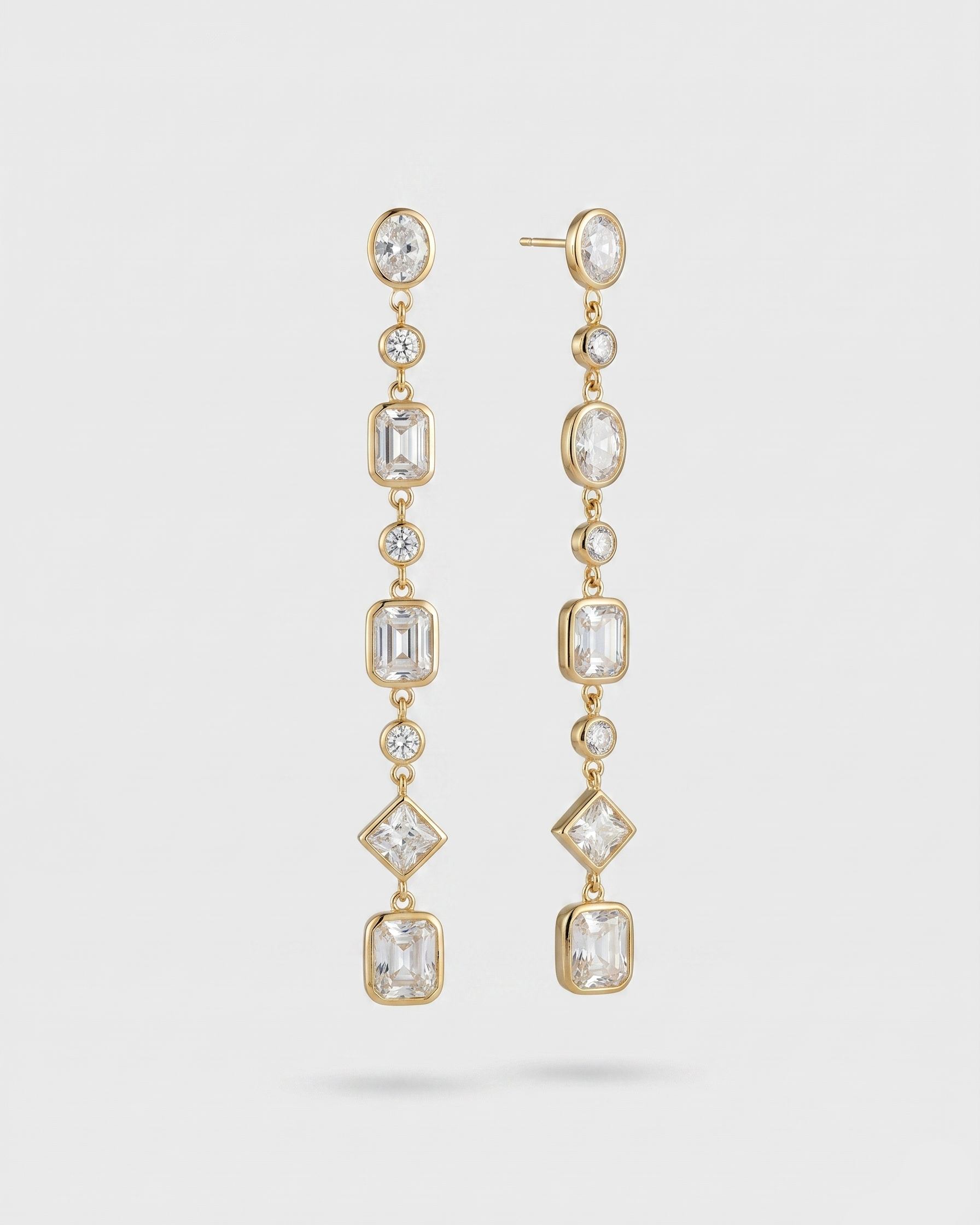 Gold earrings with clear gemstones on a white background