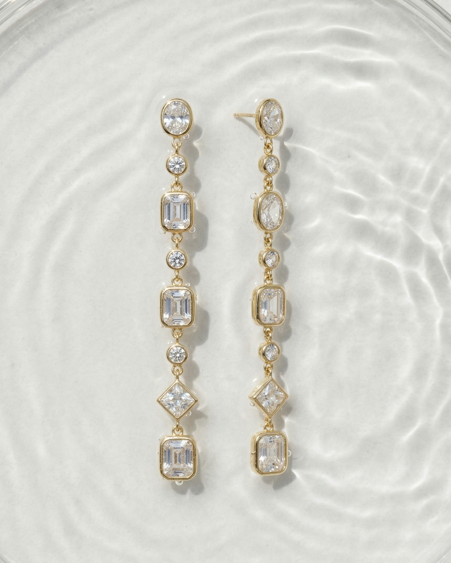 Gold earrings with clear gemstones on a white background