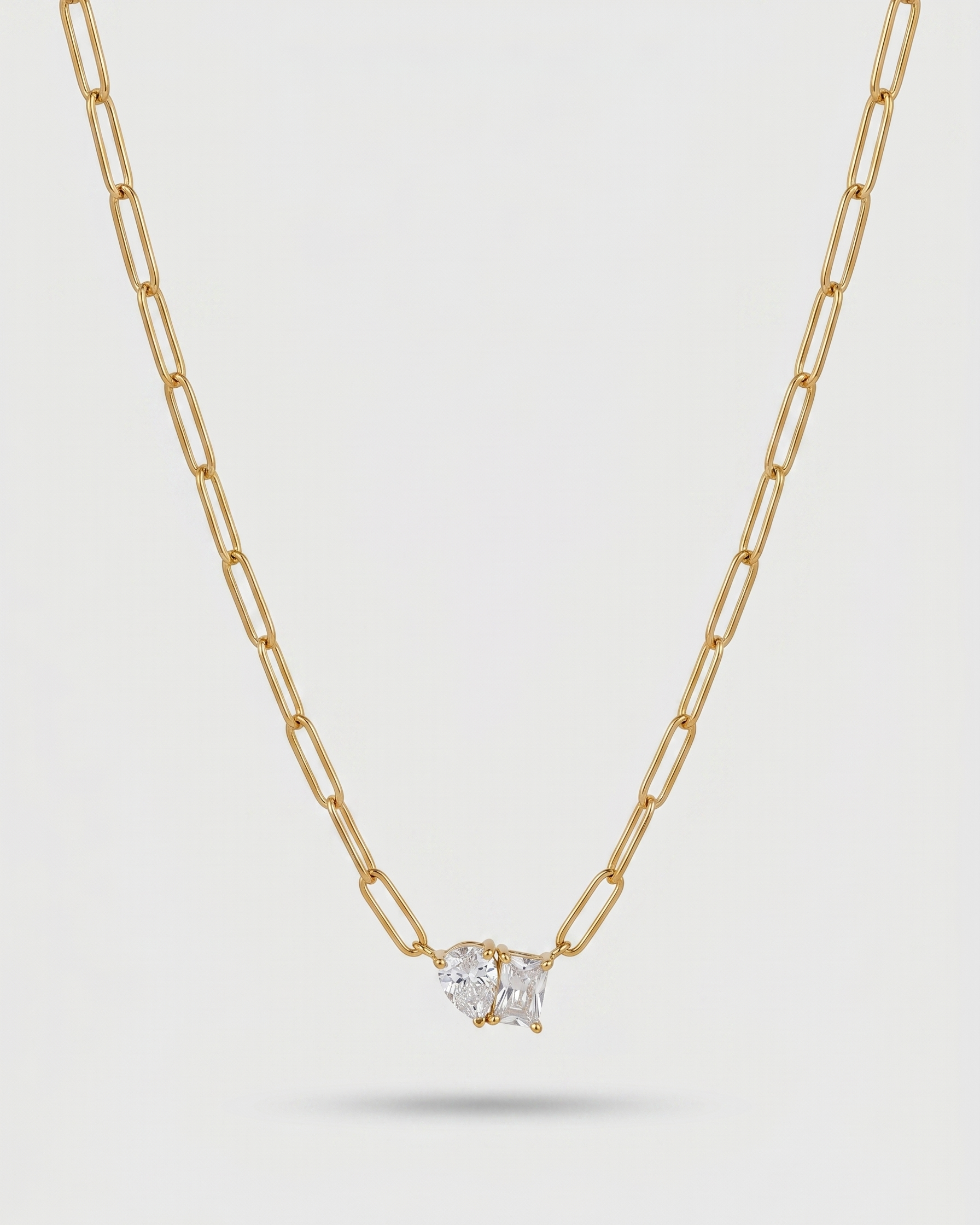 Gold necklace with a diamond pendant on a light gray background