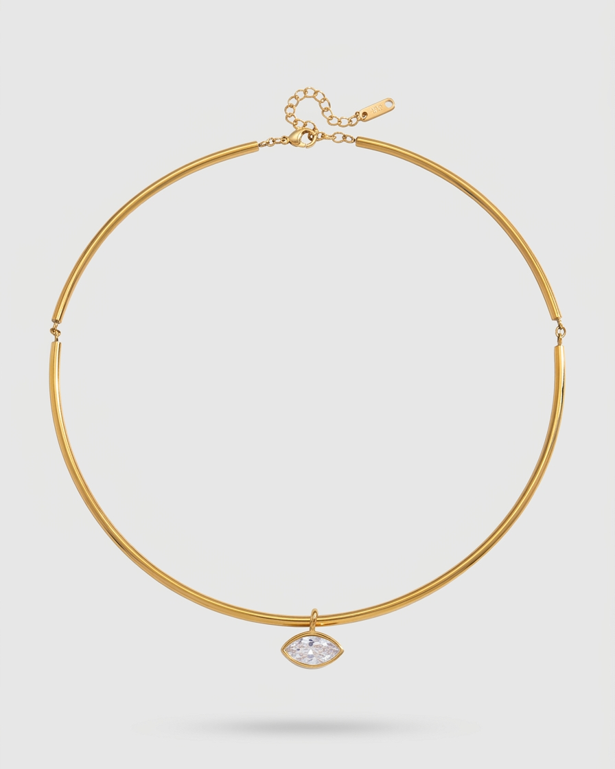 Gold necklace with a clear gemstone on a light gray background