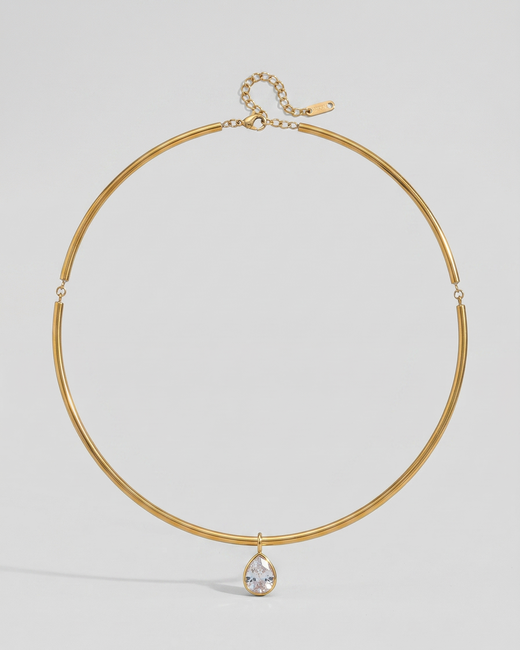 Gold necklace with a teardrop-shaped pendant on a light gray background