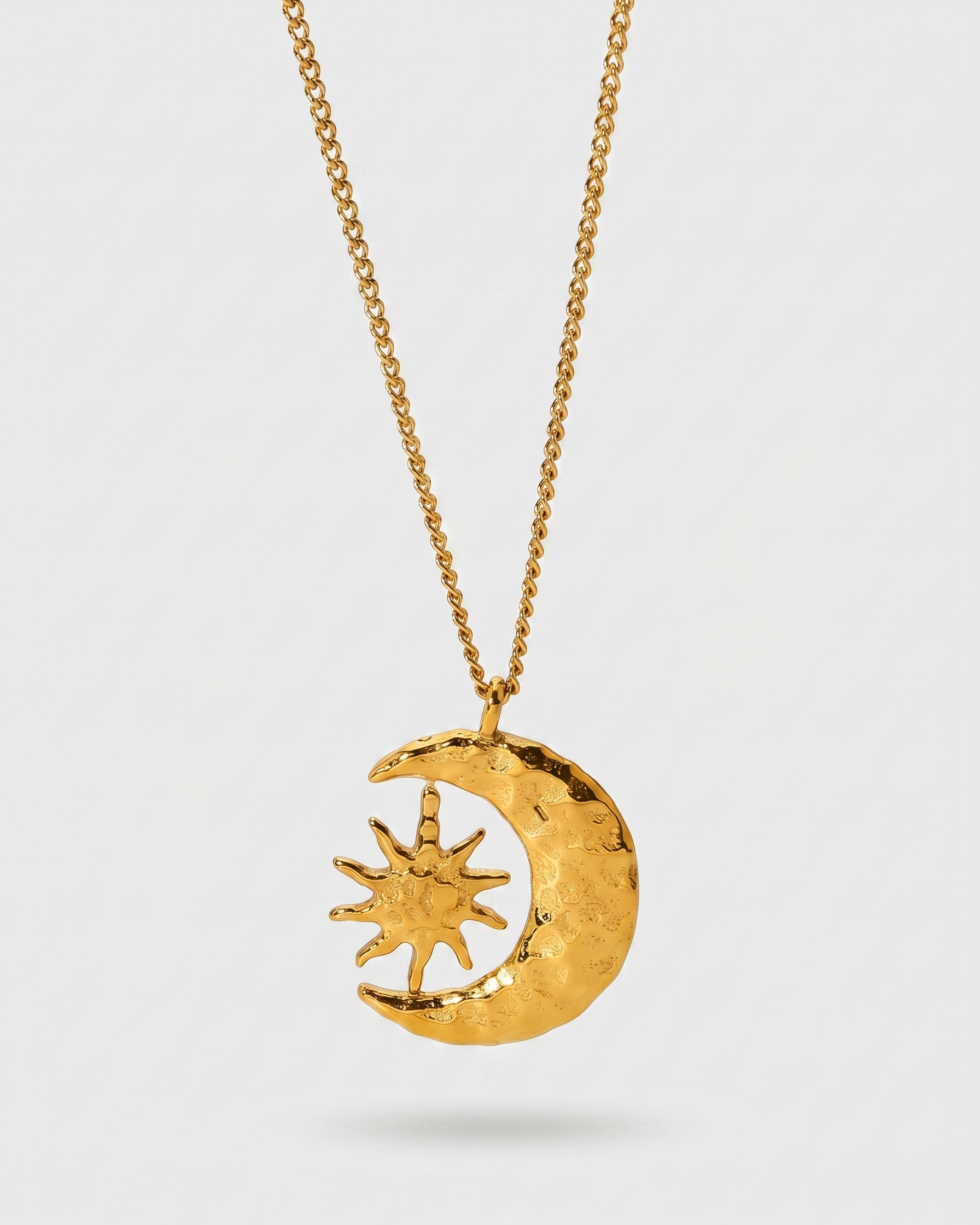 Gold necklace with a moon and sun pendant on a white background