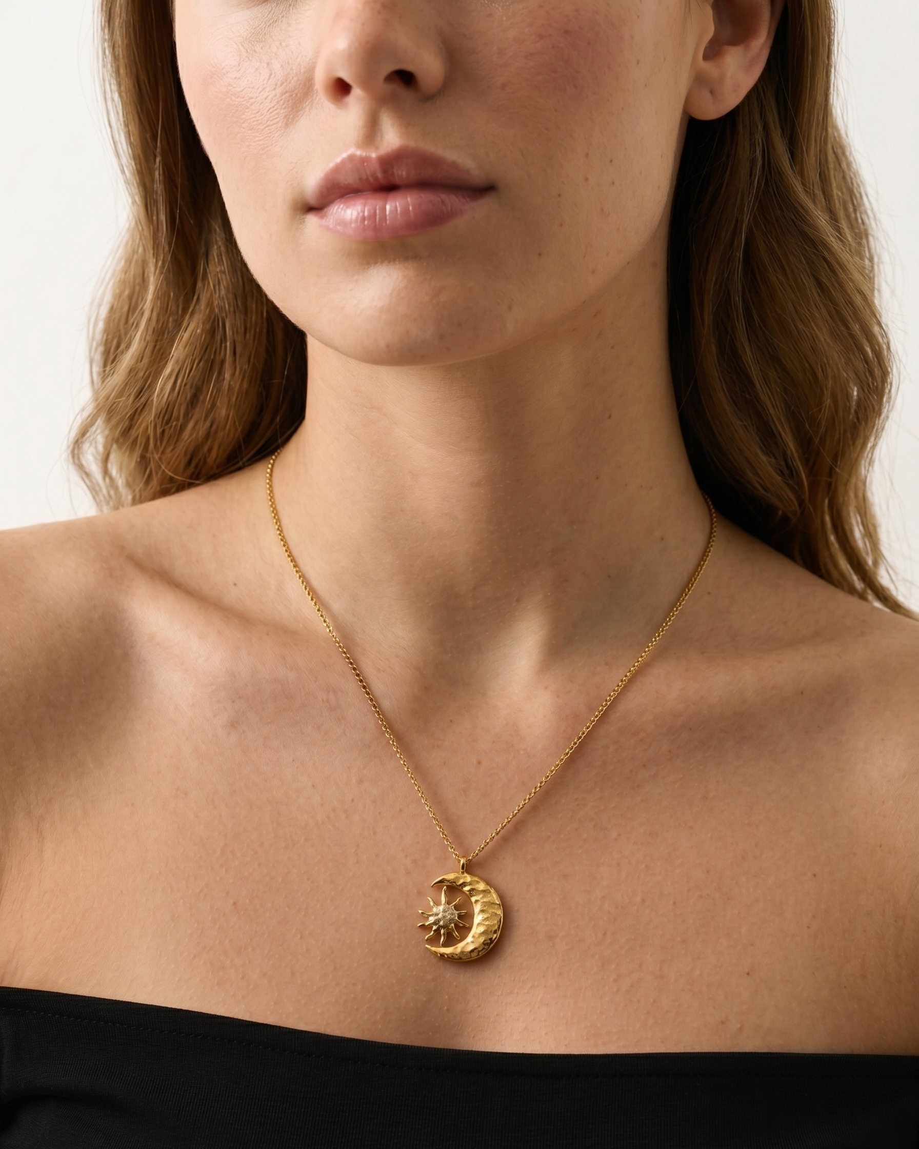 Close-up of a woman wearing a gold necklace with a pendant.