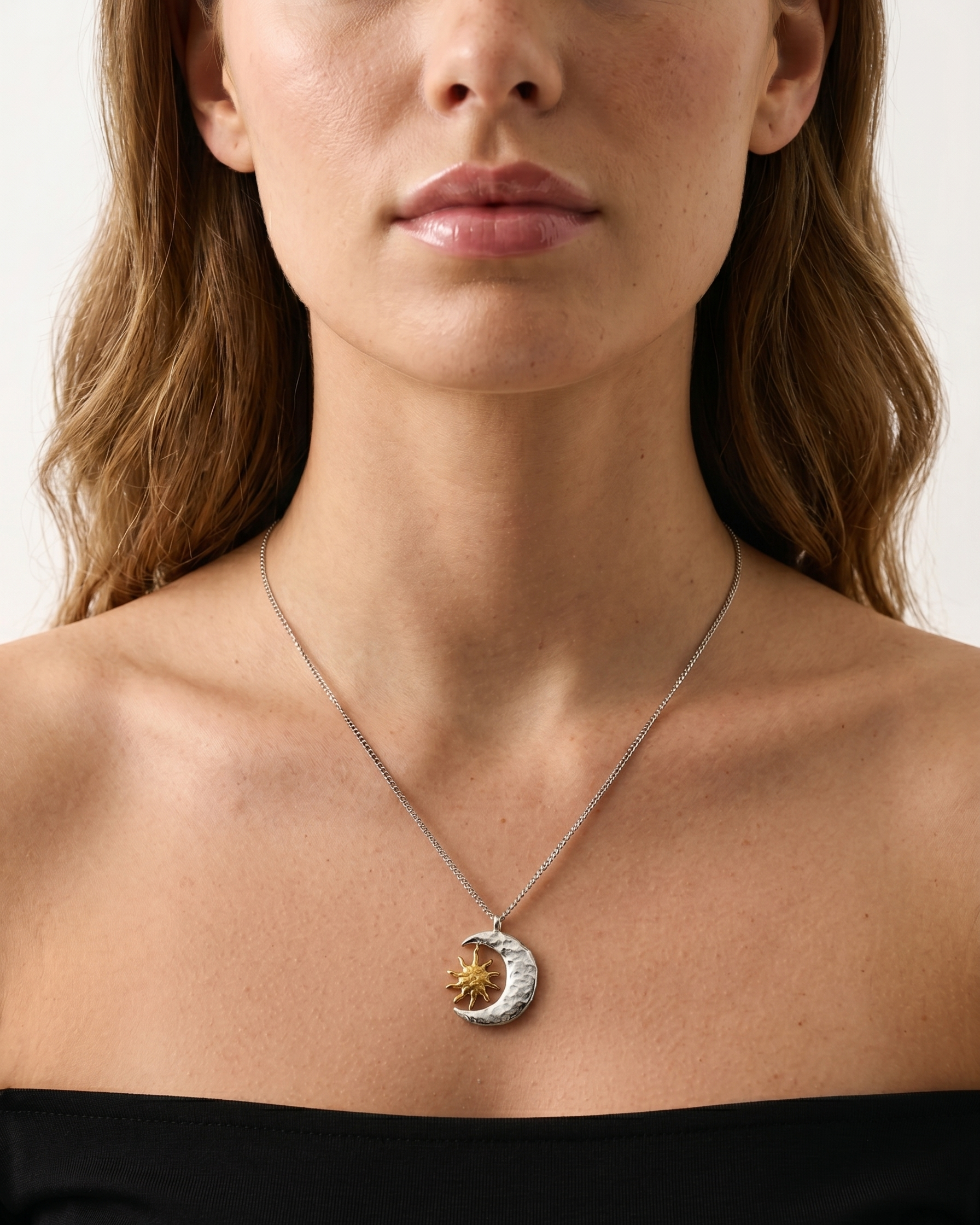 Woman wearing a necklace with a moon and star pendant on a plain background