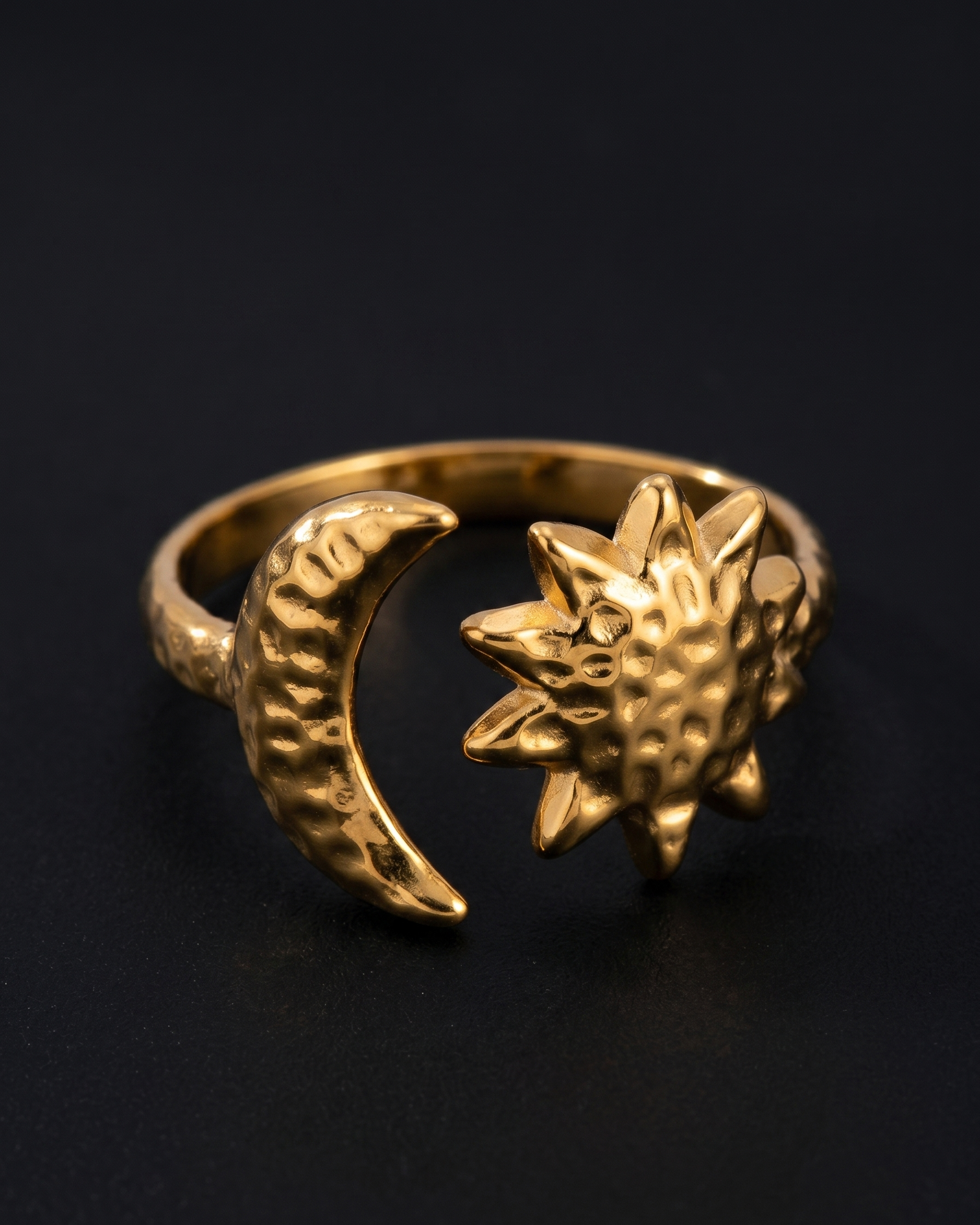 Gold ring with sun and moon design on a black background