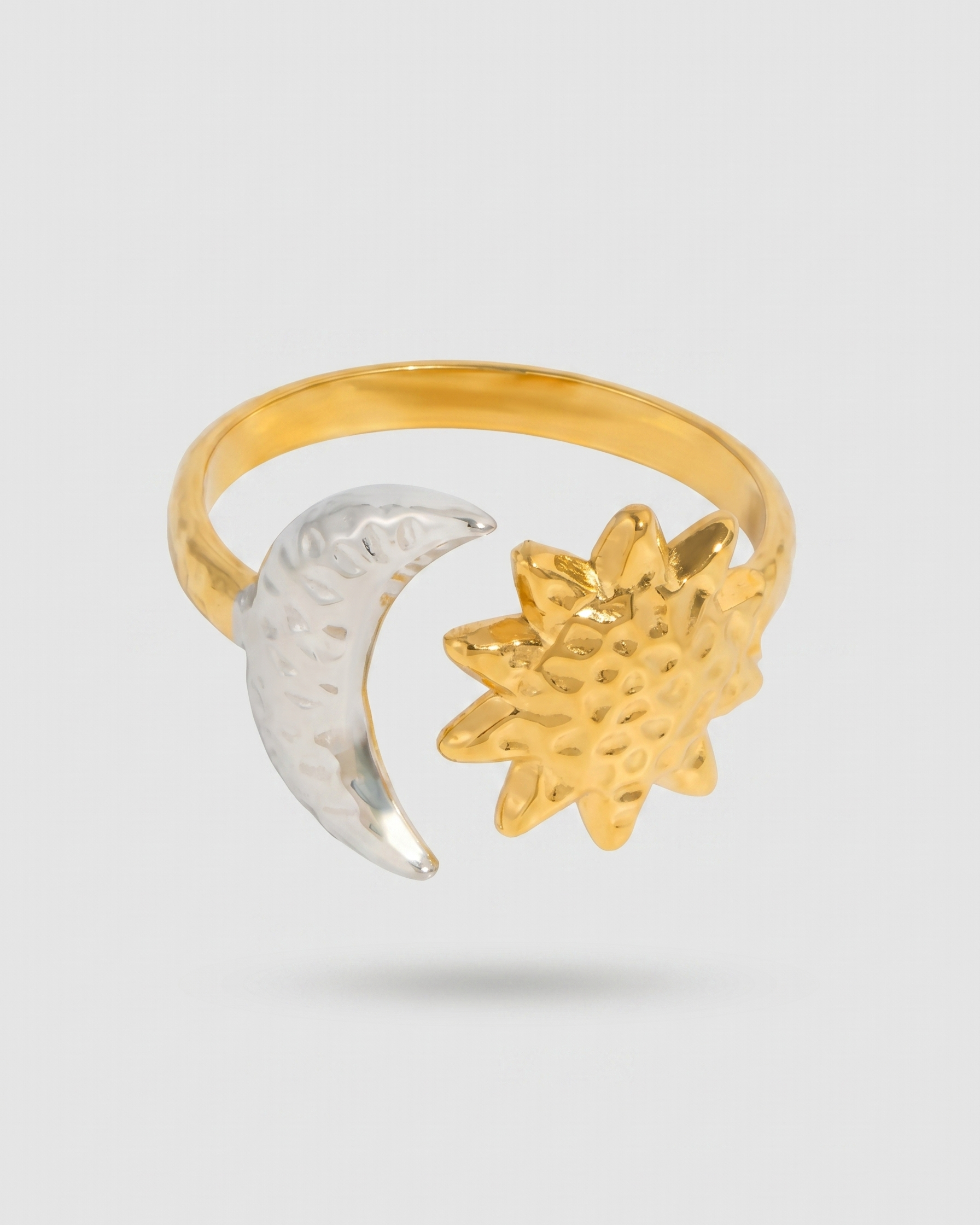 Two-toned ring with a moon and star design on a light gray background