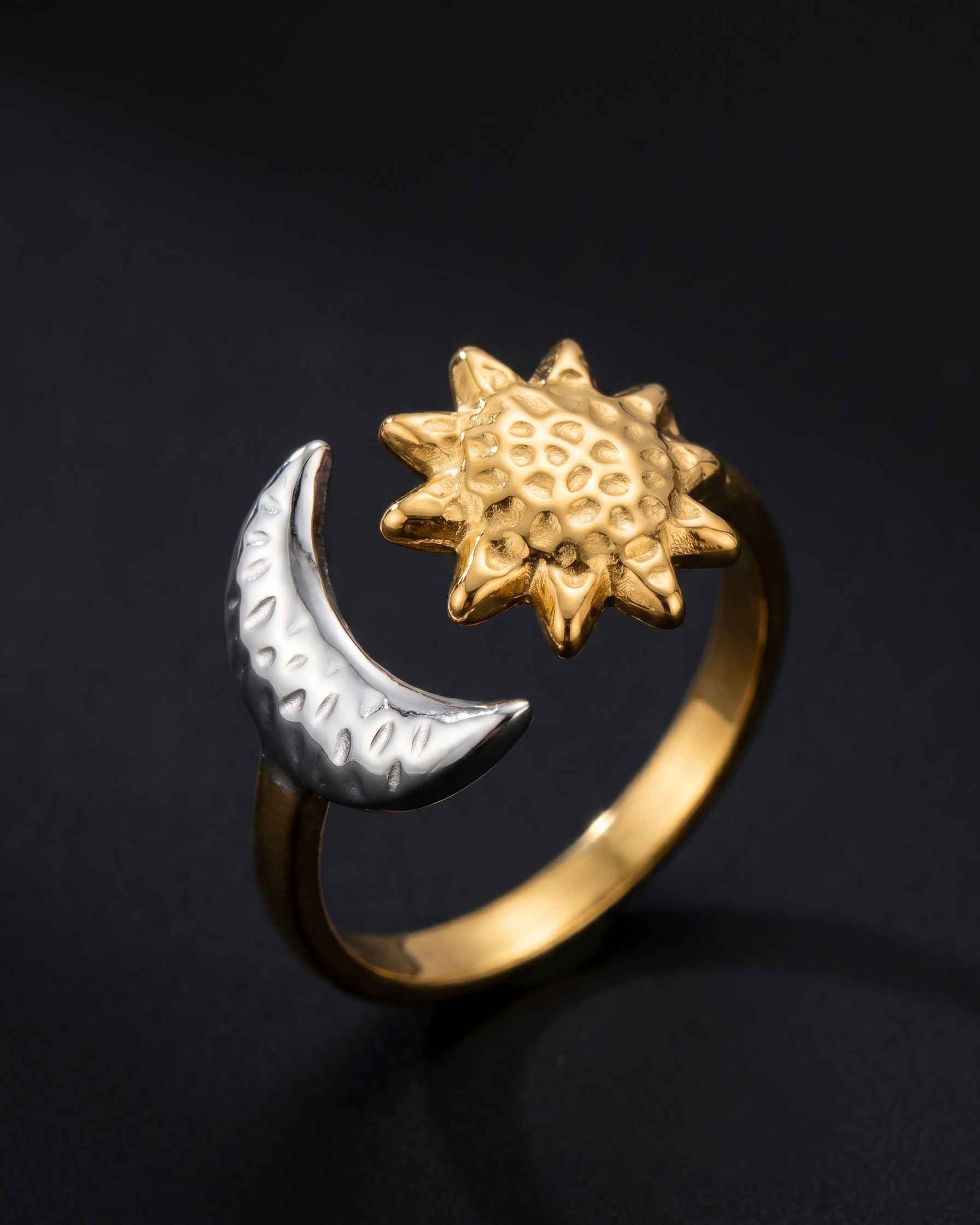 Gold and silver ring with sun and moon designs on a black background