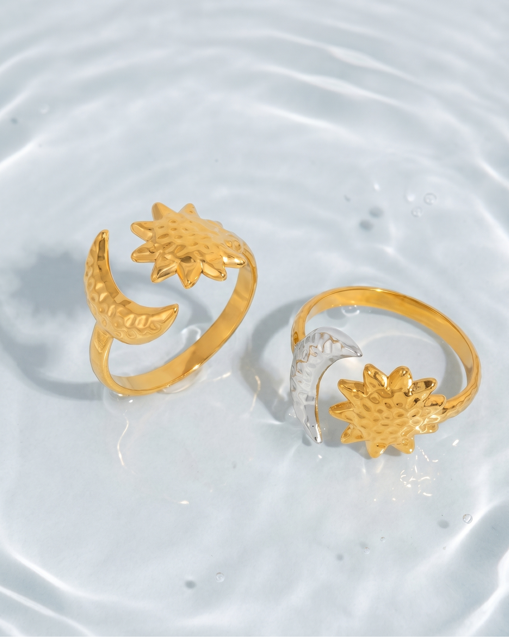Two gold rings with floral designs on a water surface